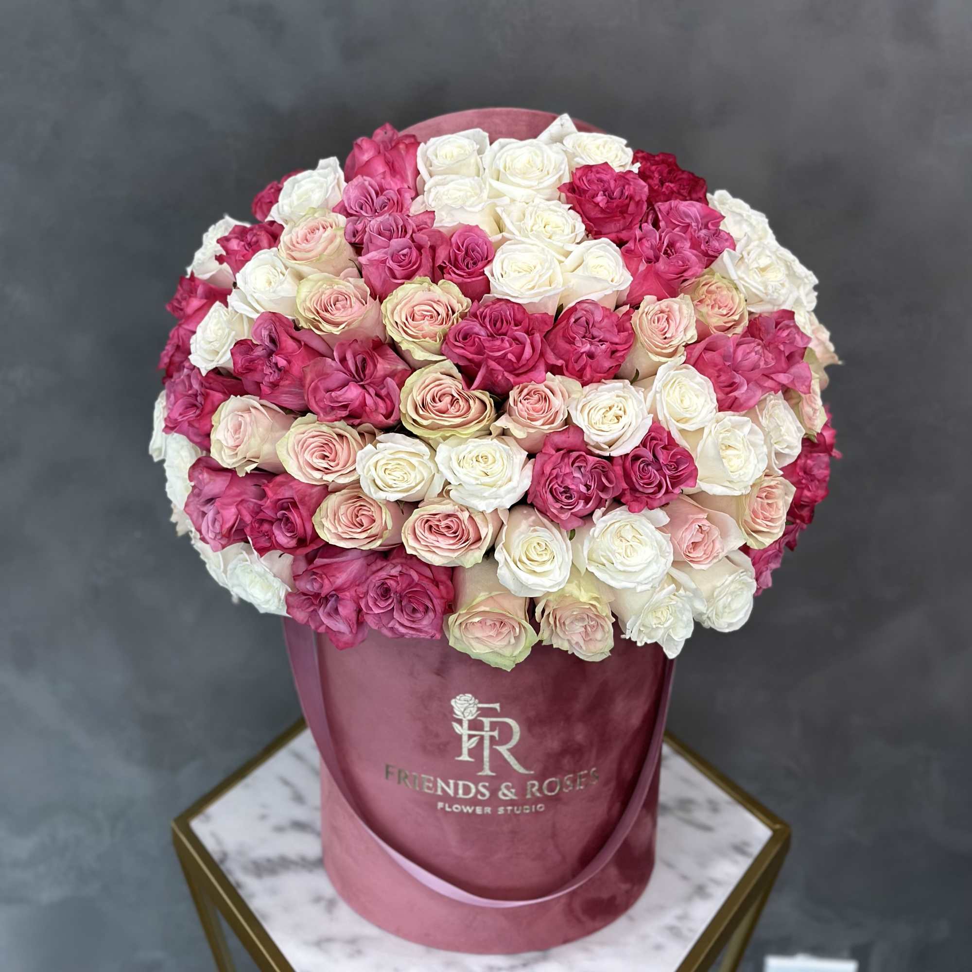 Round bouquet of pink and white roses in a pink hatbox
