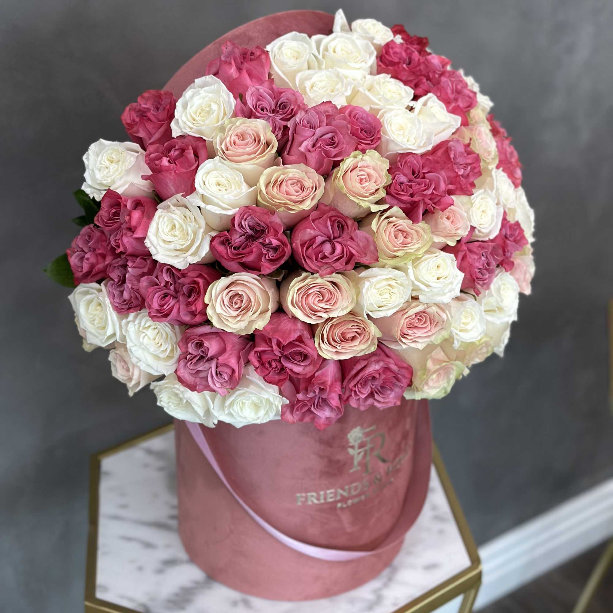 Round bouquet of pink, white, and blush roses in a pink hatbox