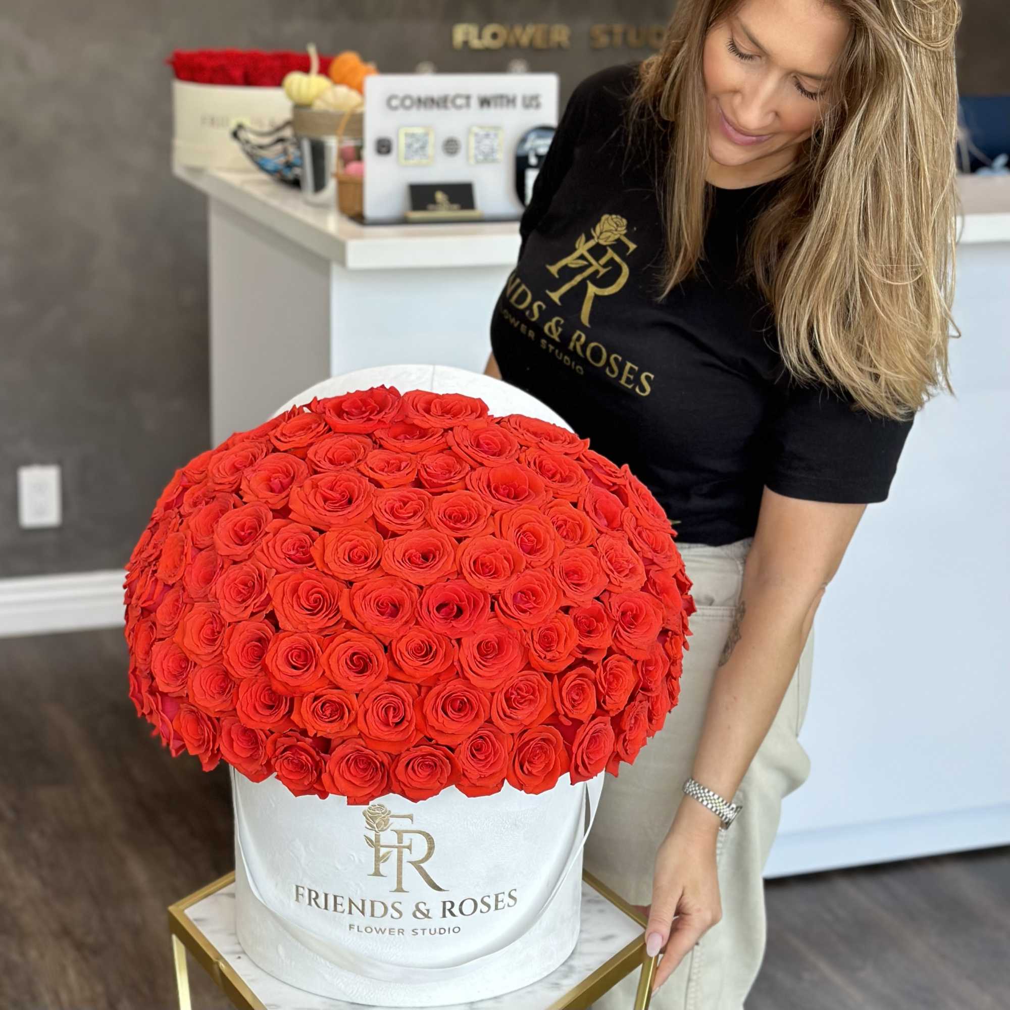 Large round box of red roses held by a woman