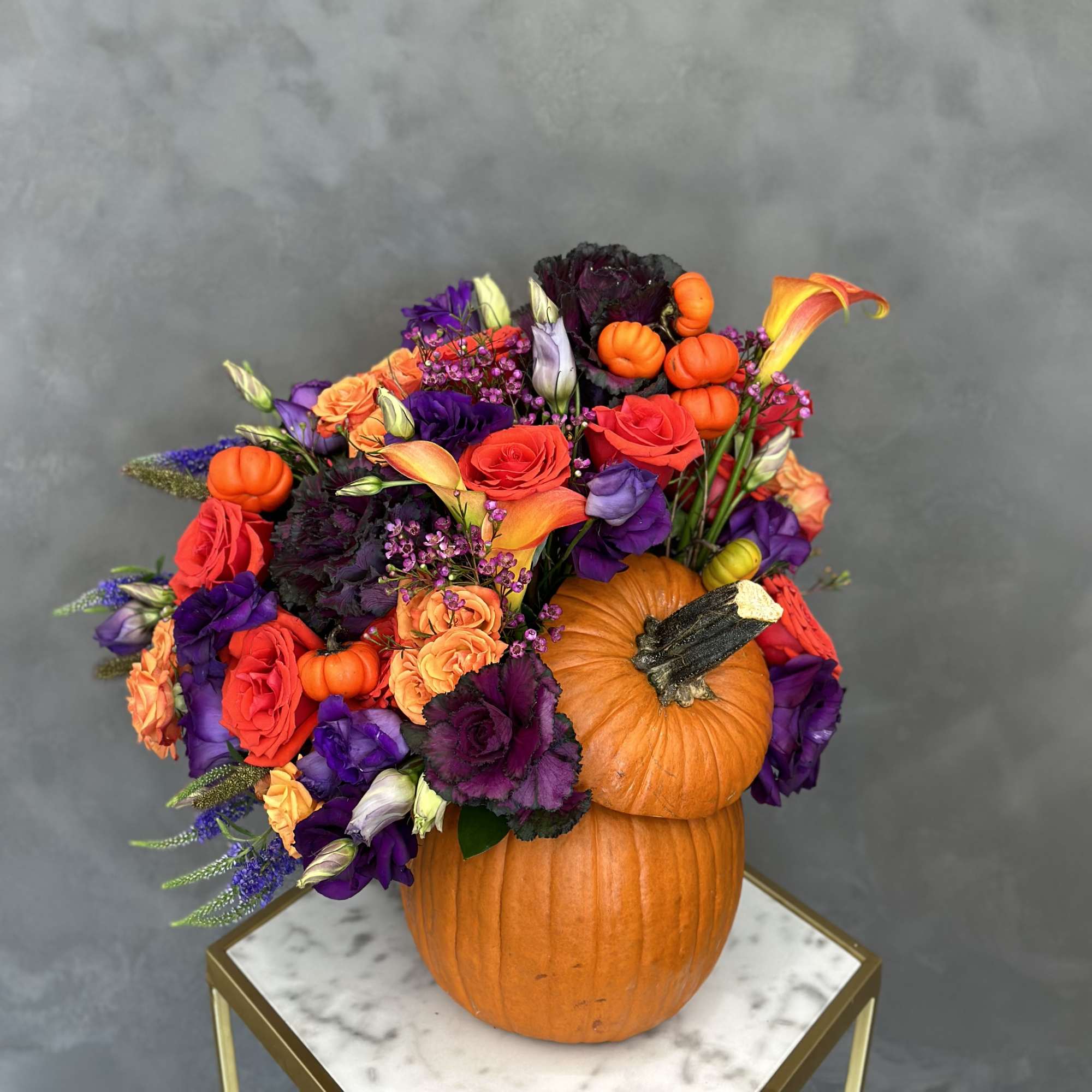 Fall floral arrangement with roses and calla lilies in stacked pumpkins