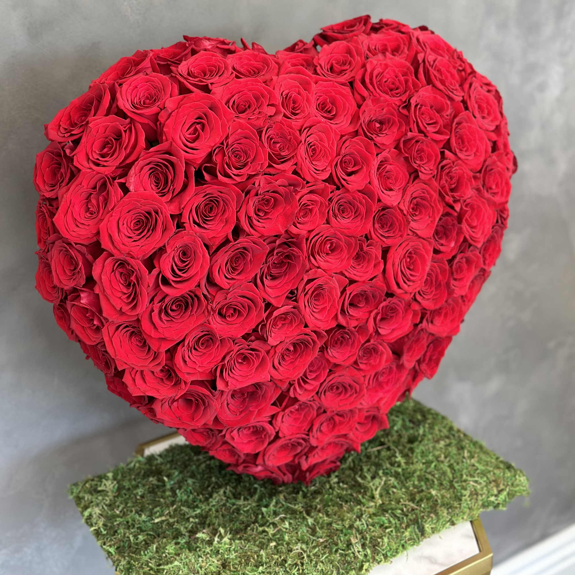 Heart-shaped bouquet of red roses on a moss-covered base