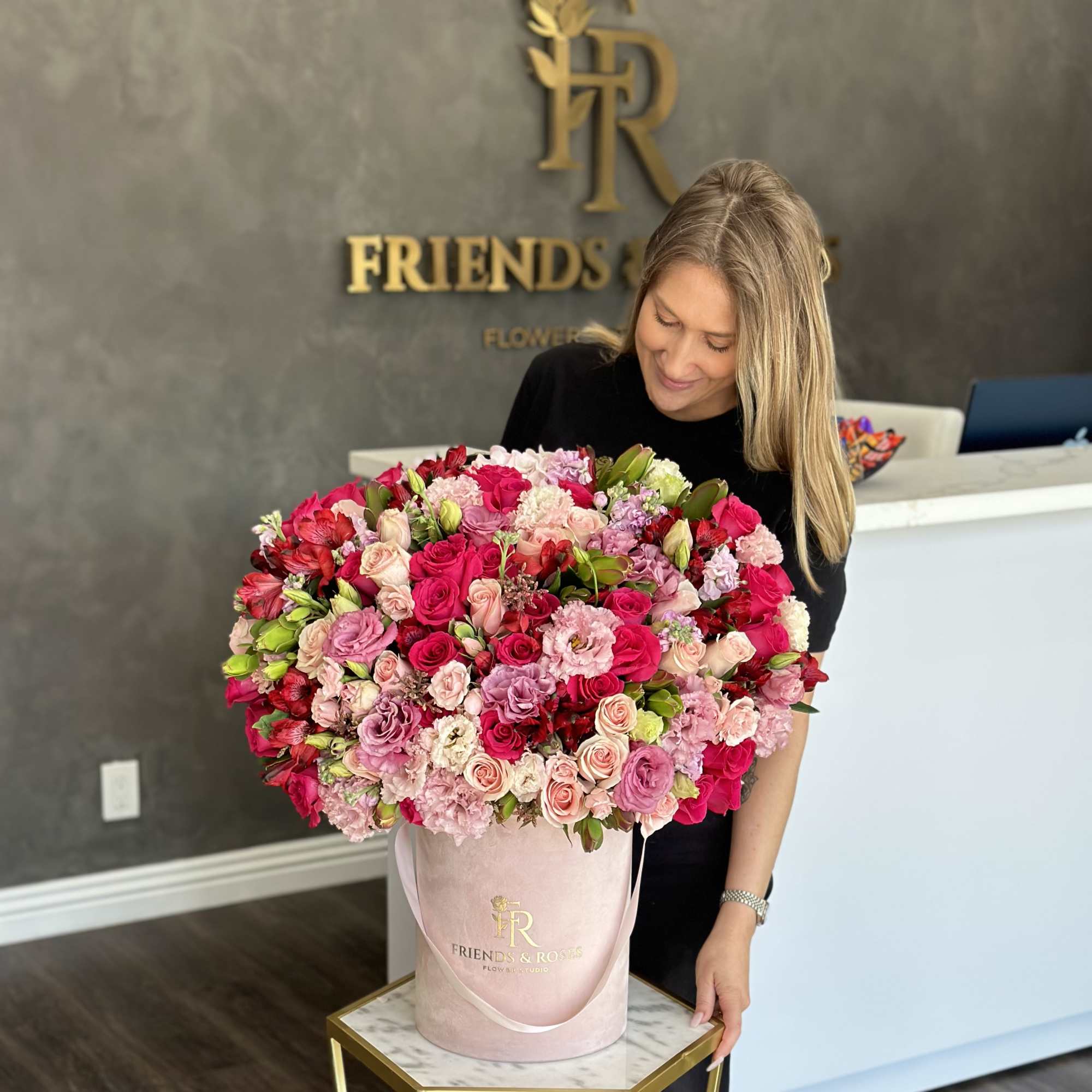 Large pink and red rose arrangement in a blush hatbox