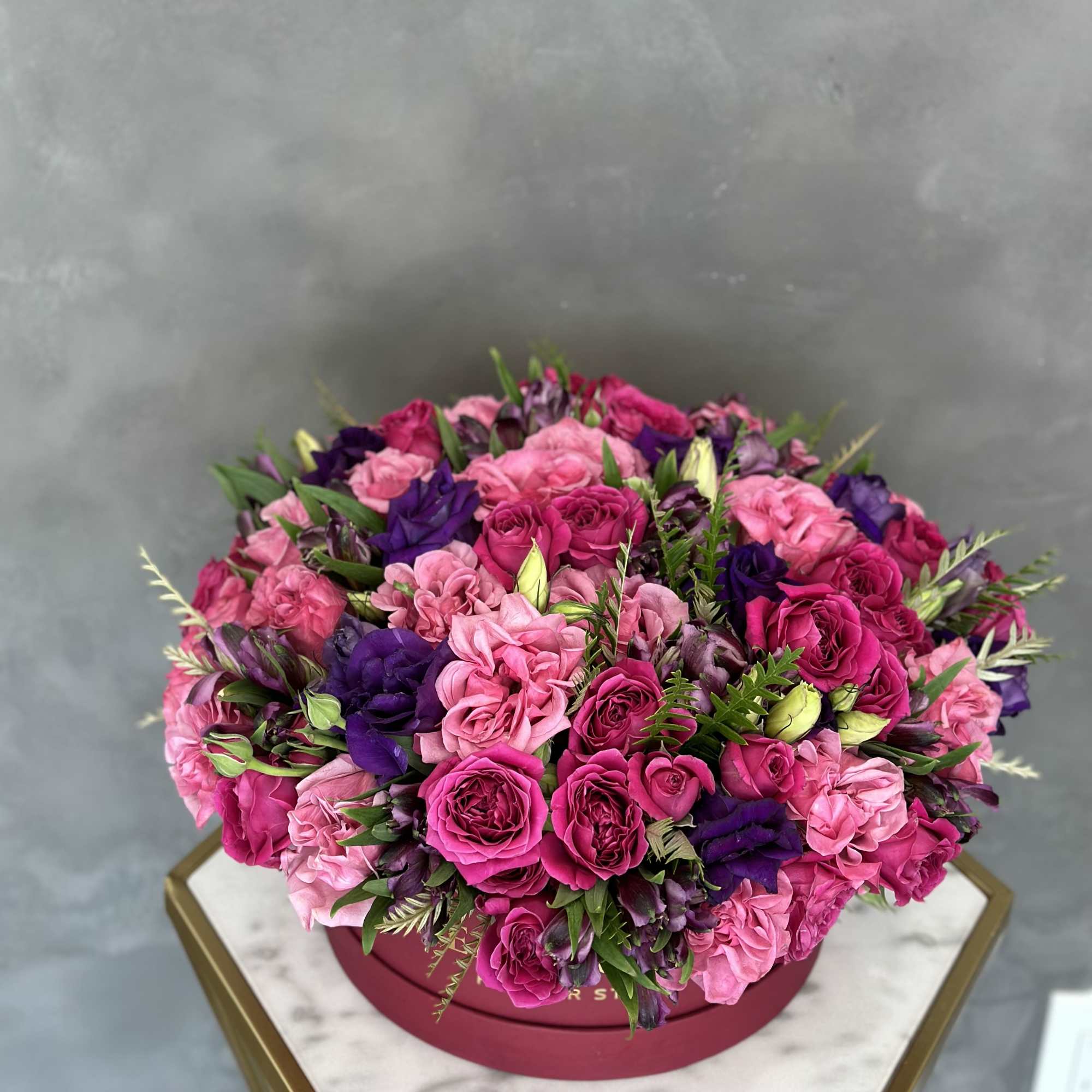 Pink and purple rose bouquet in a round box
