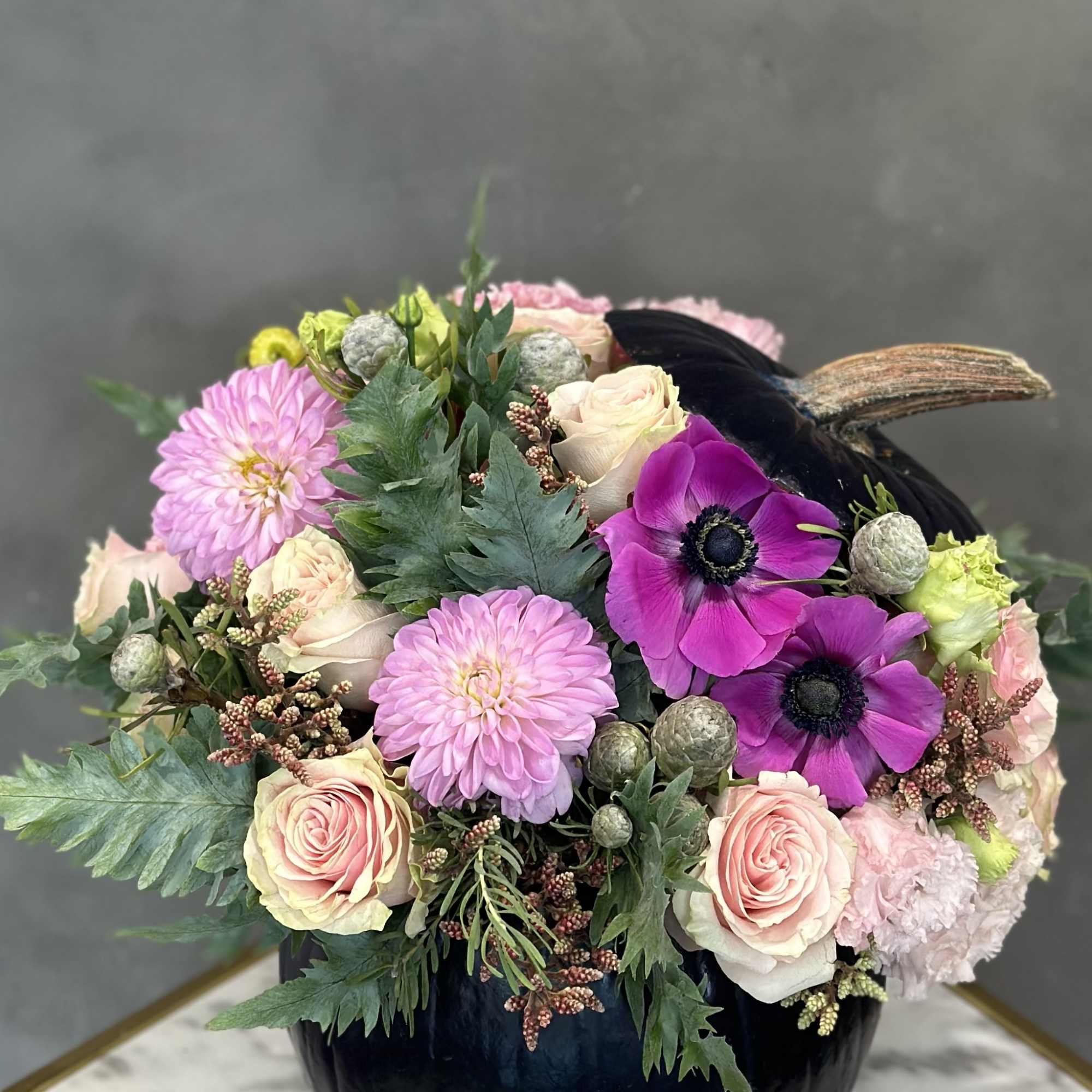 Bouquet of pink and cream flowers in a black pumpkin vase