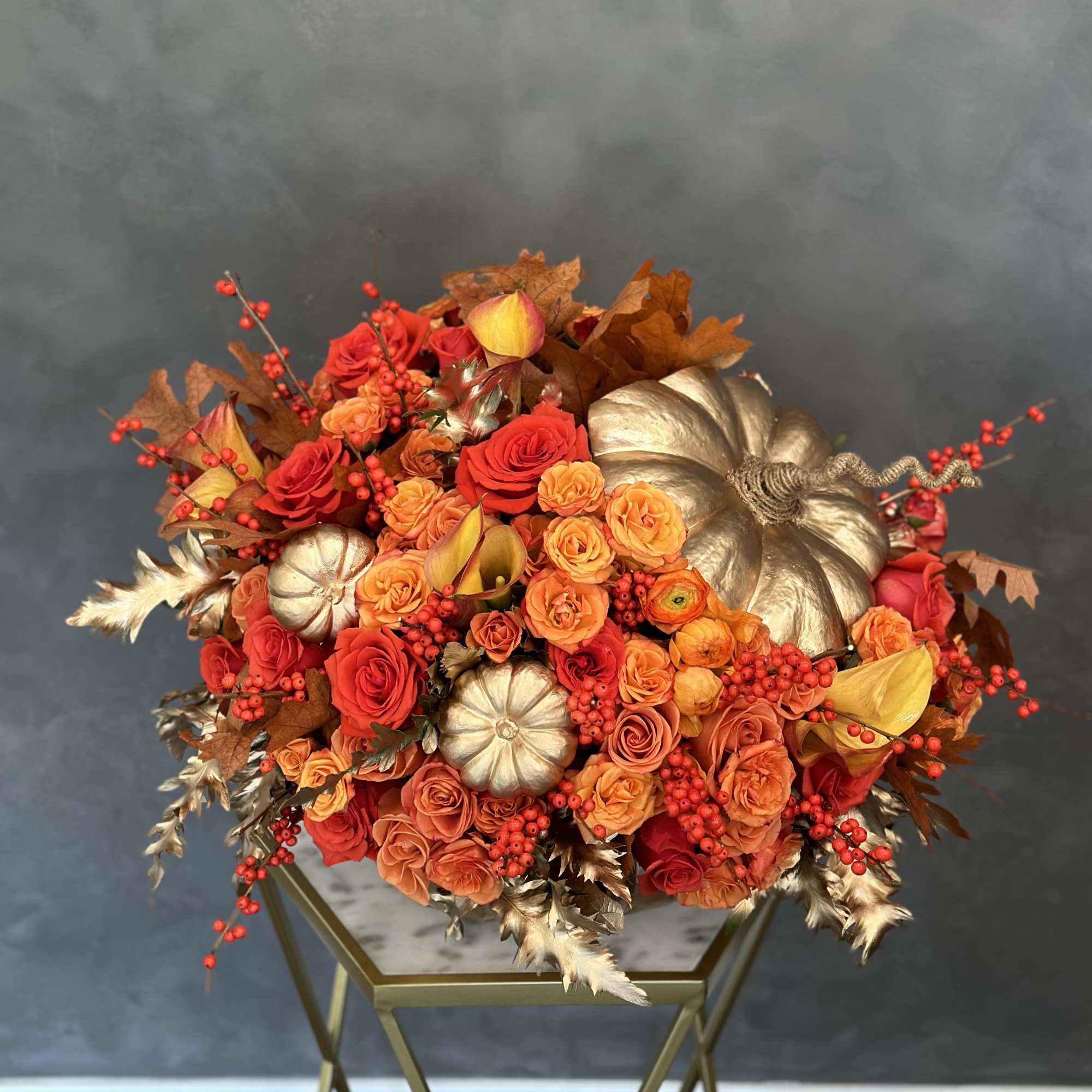 Orange and red rose bouquet with gold pumpkins and berry sprigs