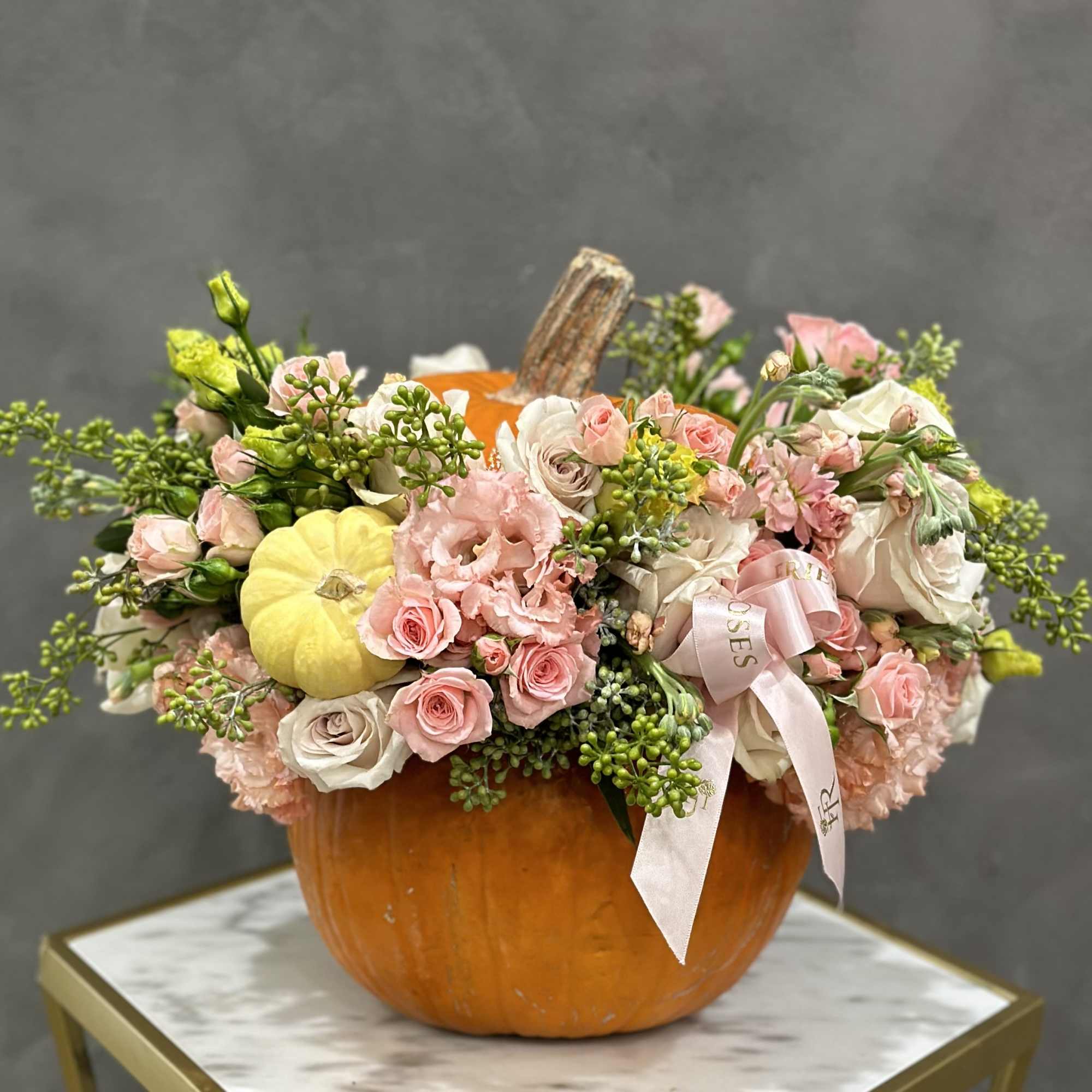 Floral arrangement in a pumpkin vase with pink and white blooms