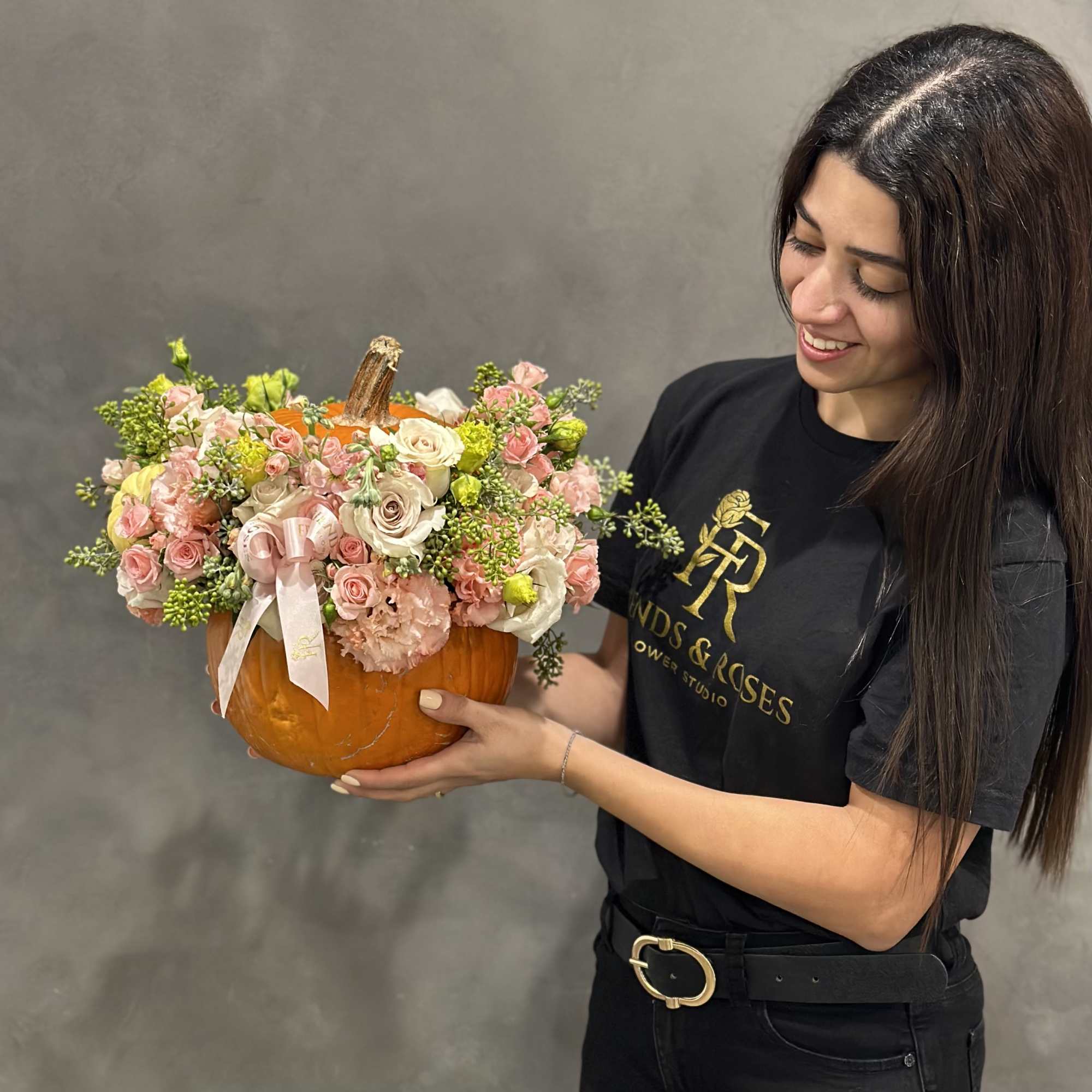 Woman holding a pumpkin-shaped floral arrangement with pink and white flowers