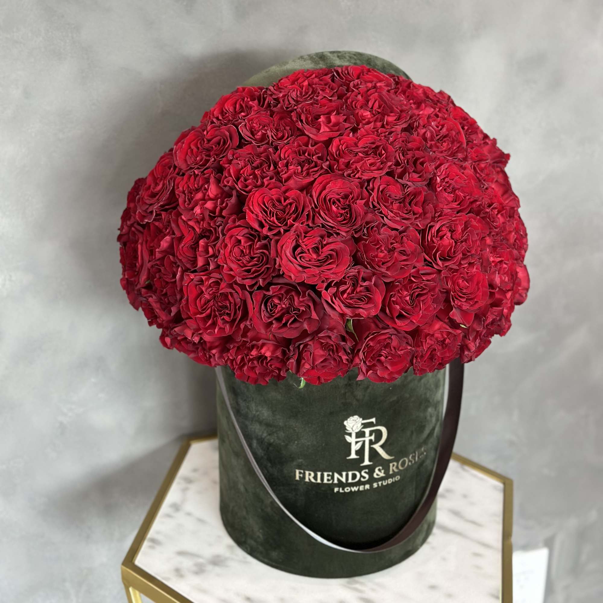 Large red rose arrangement in a dark green hat box