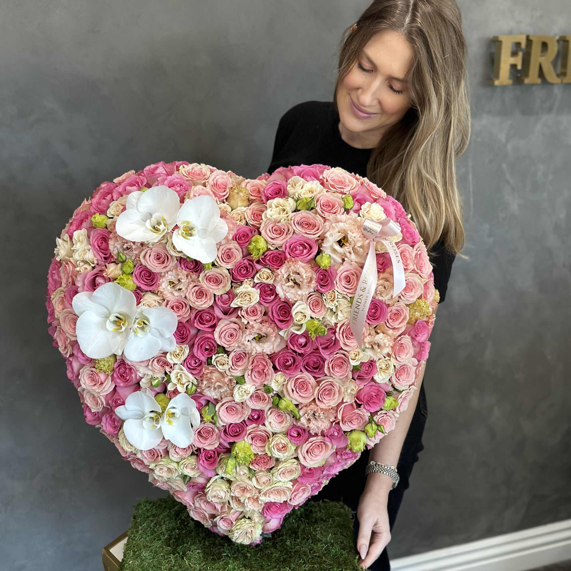 Heart-shaped arrangement of pink roses with white orchids
