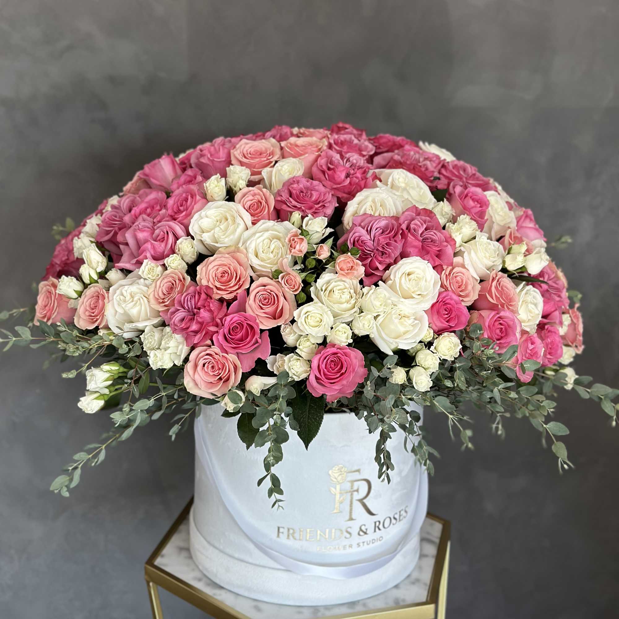 Pink and white roses arranged in a white hat box
