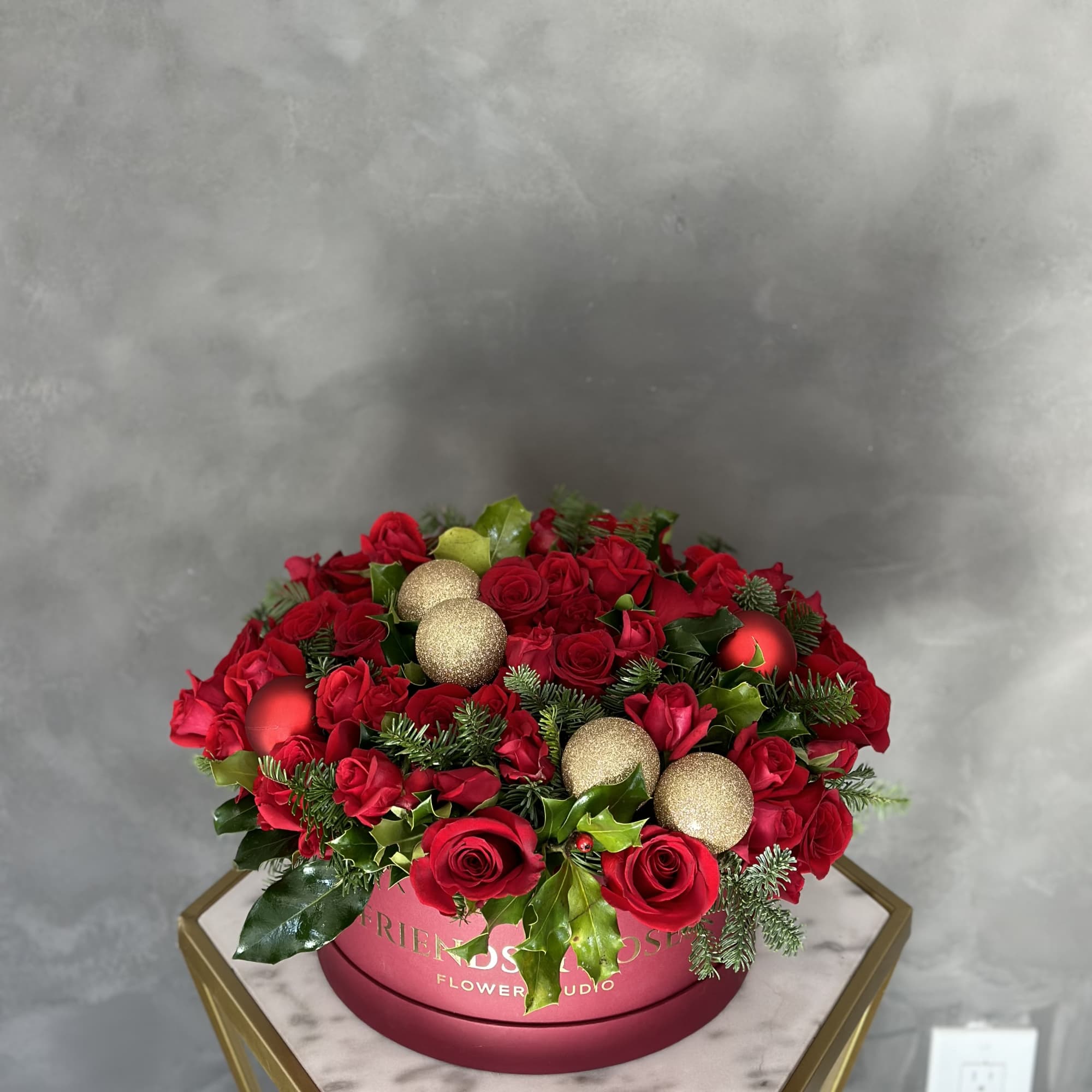 Red roses arranged in a round box with gold ornaments