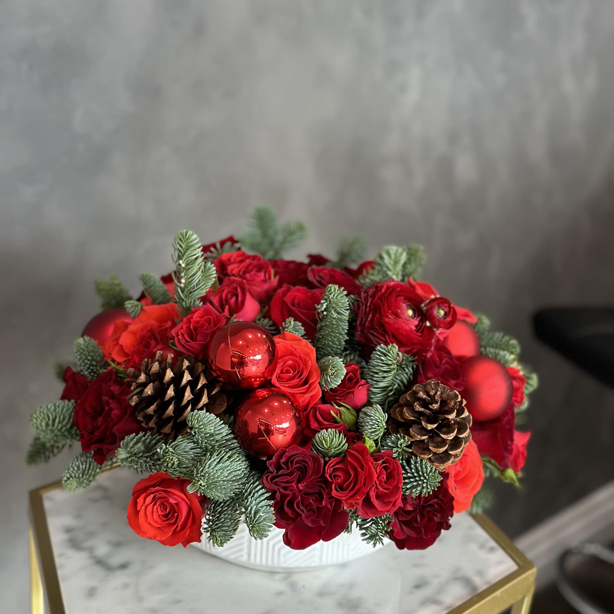 Red roses and pinecones in a white bowl with red ornaments