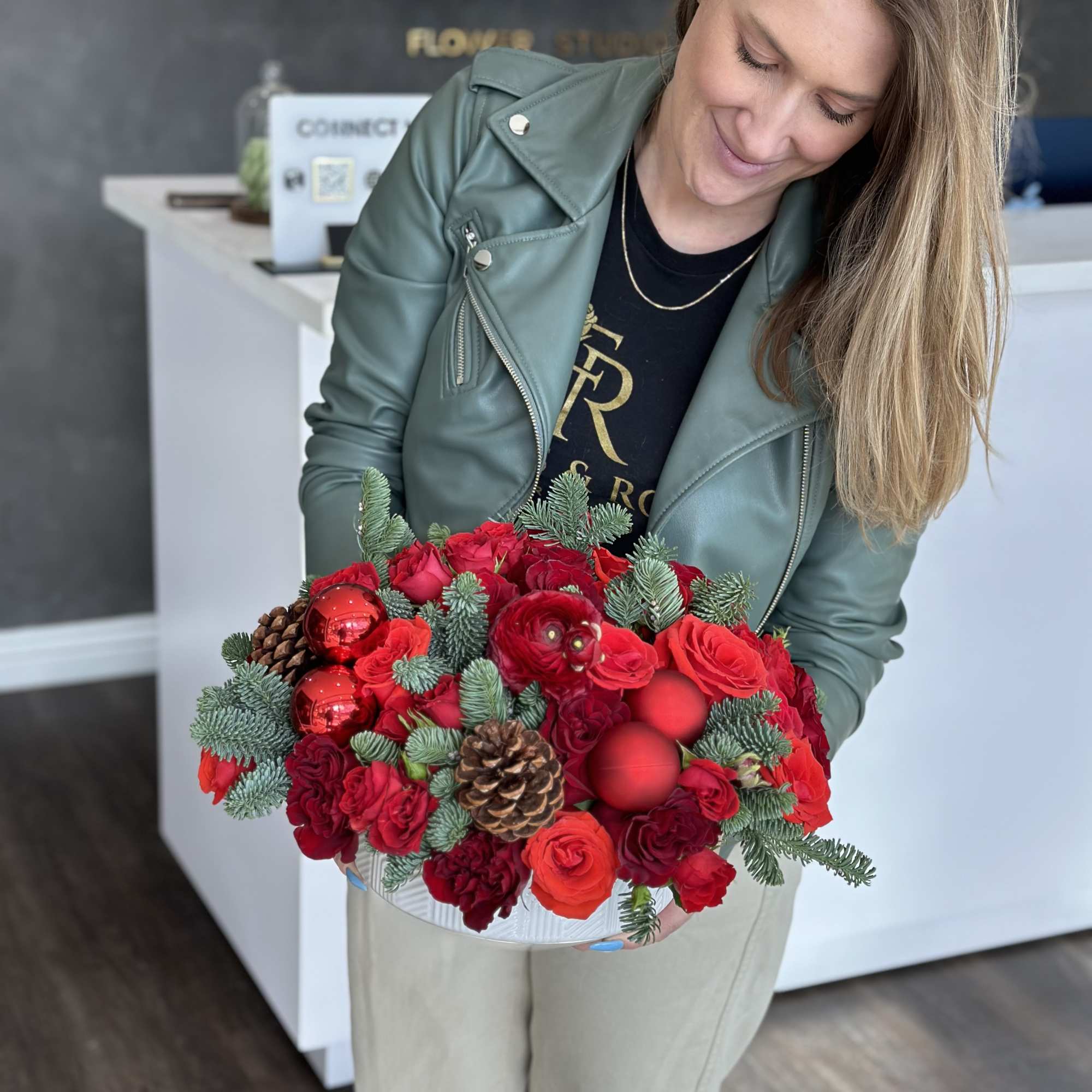 Woman holding a red rose arrangement with pinecones and ornaments
