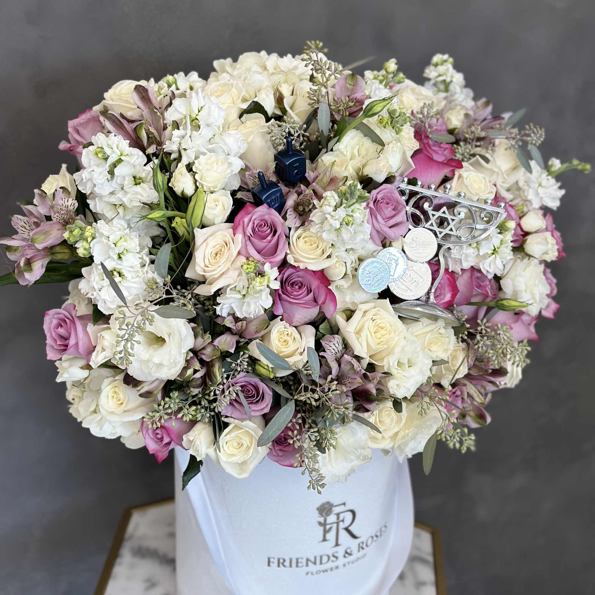 Large bouquet of pink and white roses in a white hatbox