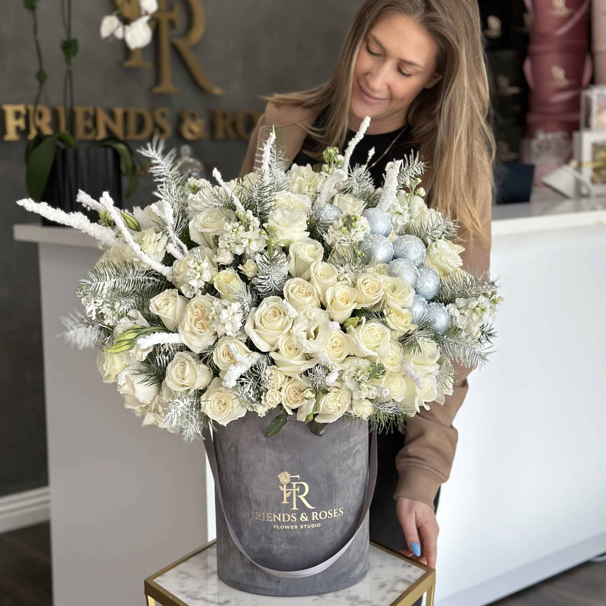 Large white rose arrangement in a gray hatbox with silver ornaments
