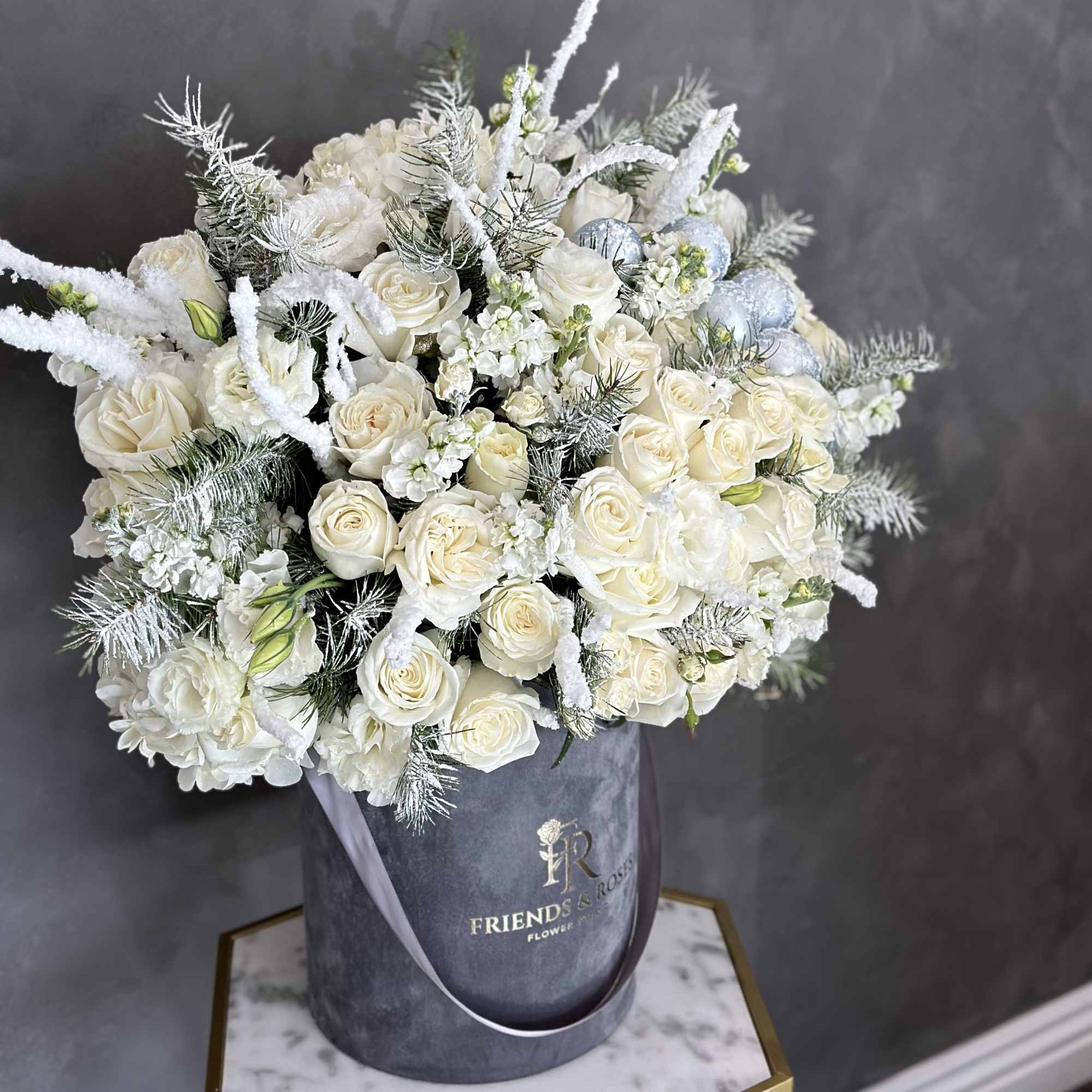White rose bouquet in a gray hatbox with frosted accents