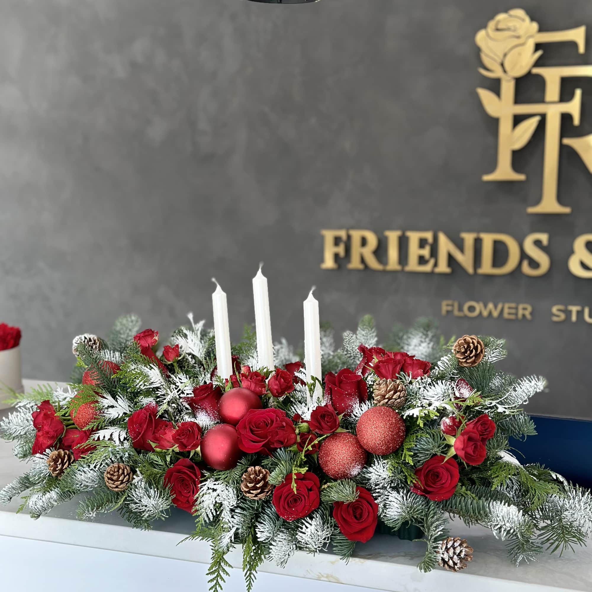 Red rose centerpiece with white candles and pinecones