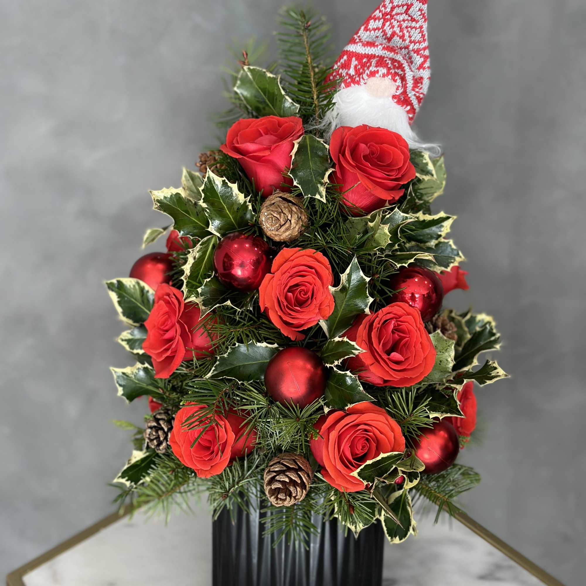 Christmas arrangement with red roses, ornaments, and a Santa hat