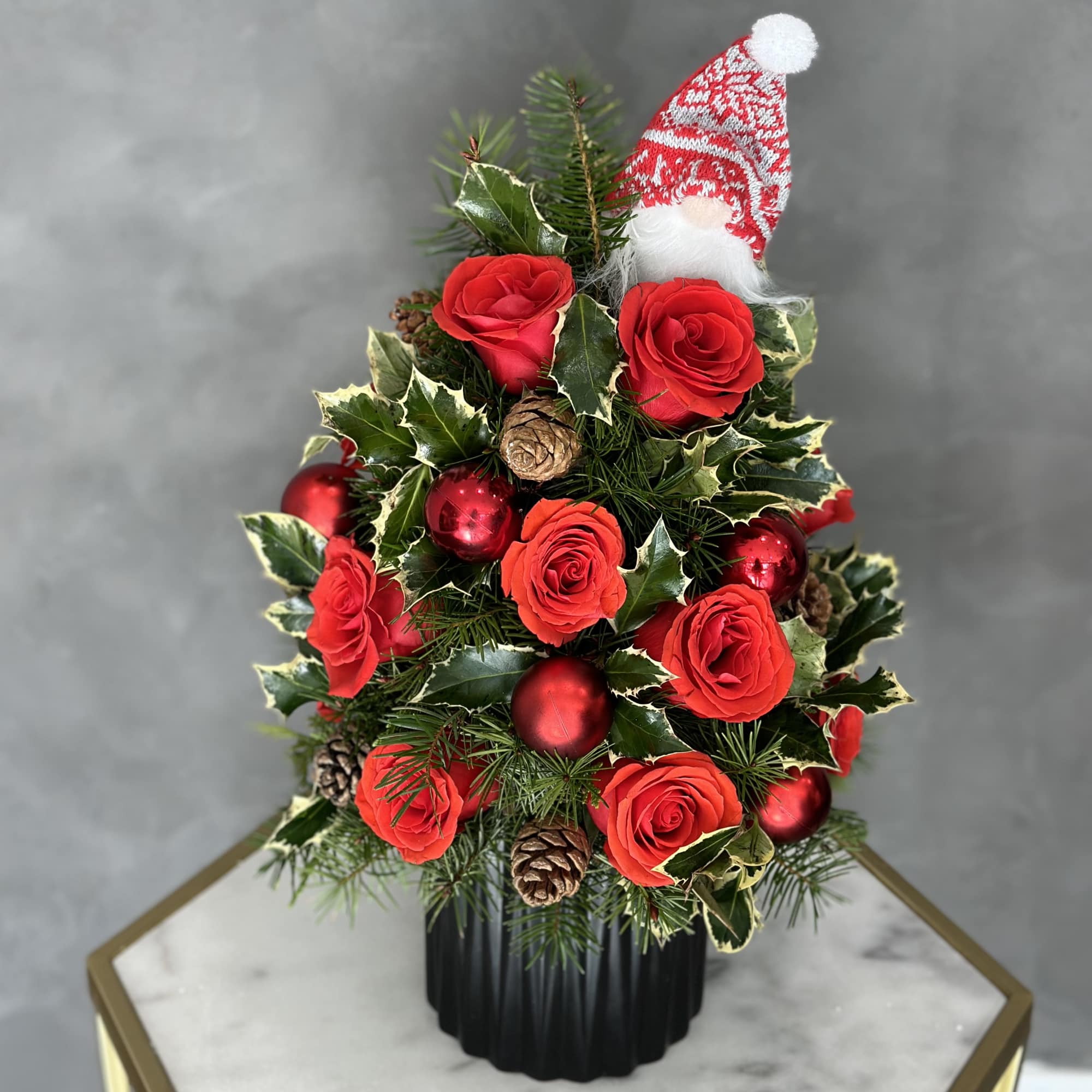 Small Christmas tree arrangement with red roses, ornaments, and a Santa hat