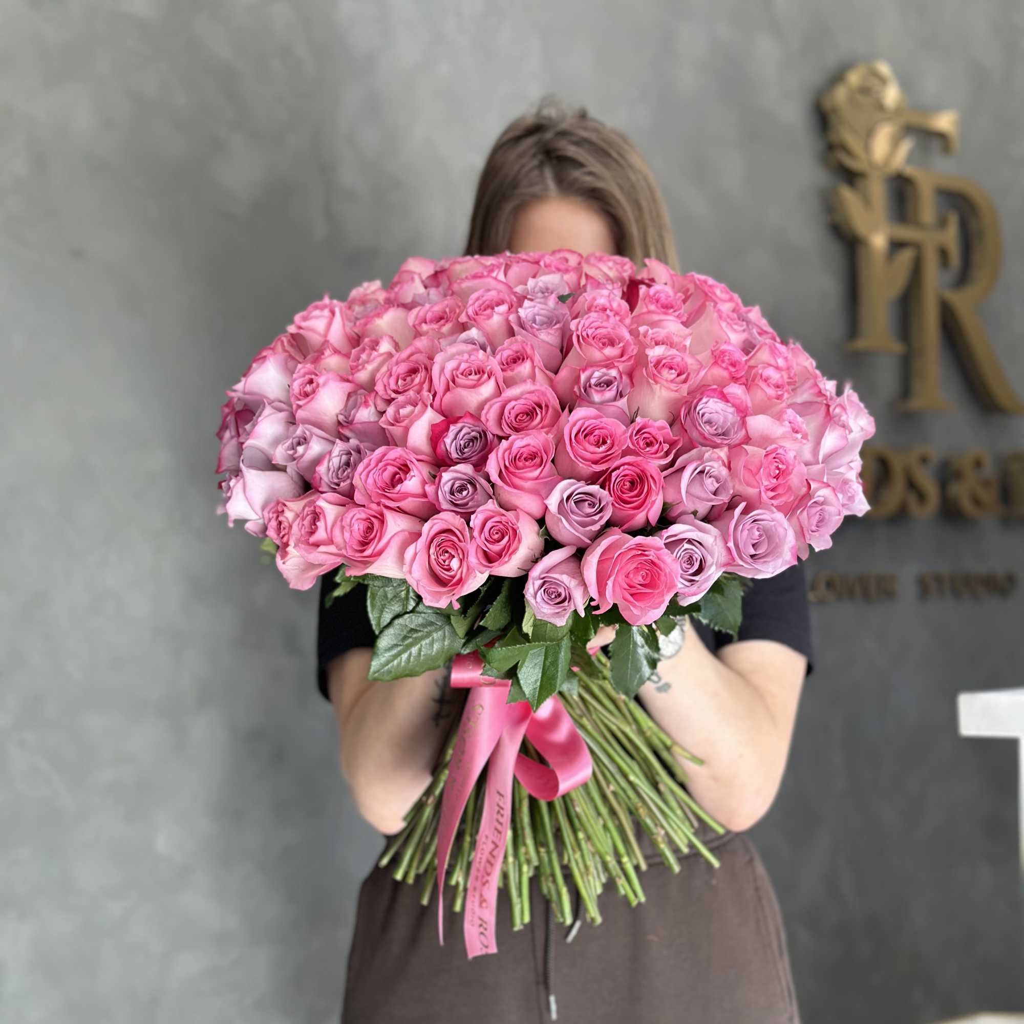 Large bouquet of pink roses held in front of a person