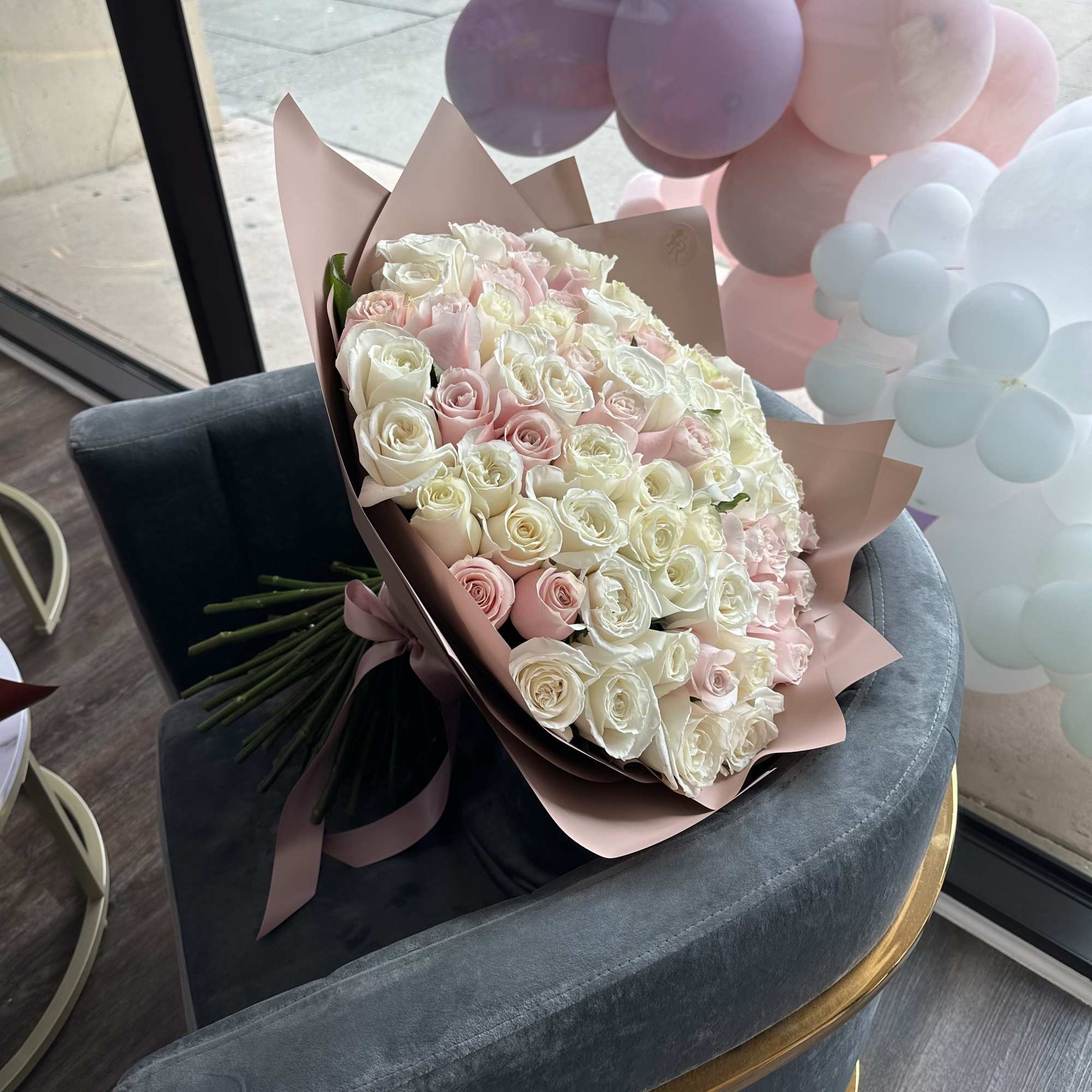 Bouquet of white and pale pink roses wrapped in blush paper