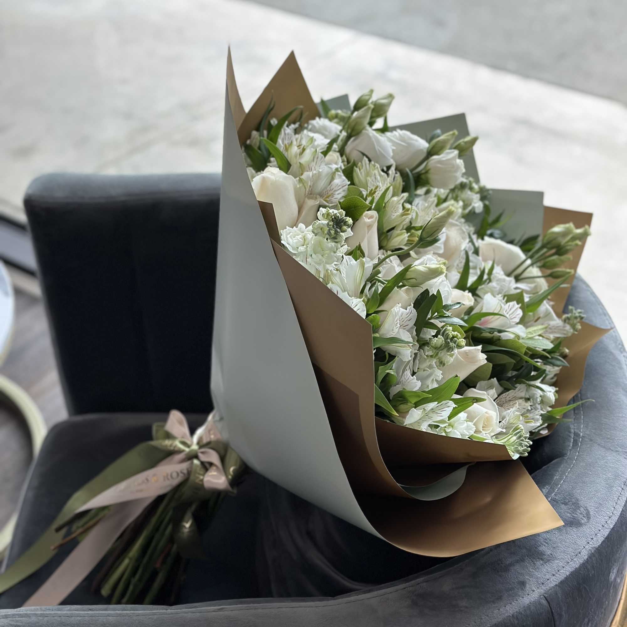 White bouquet wrapped in brown and gray paper
