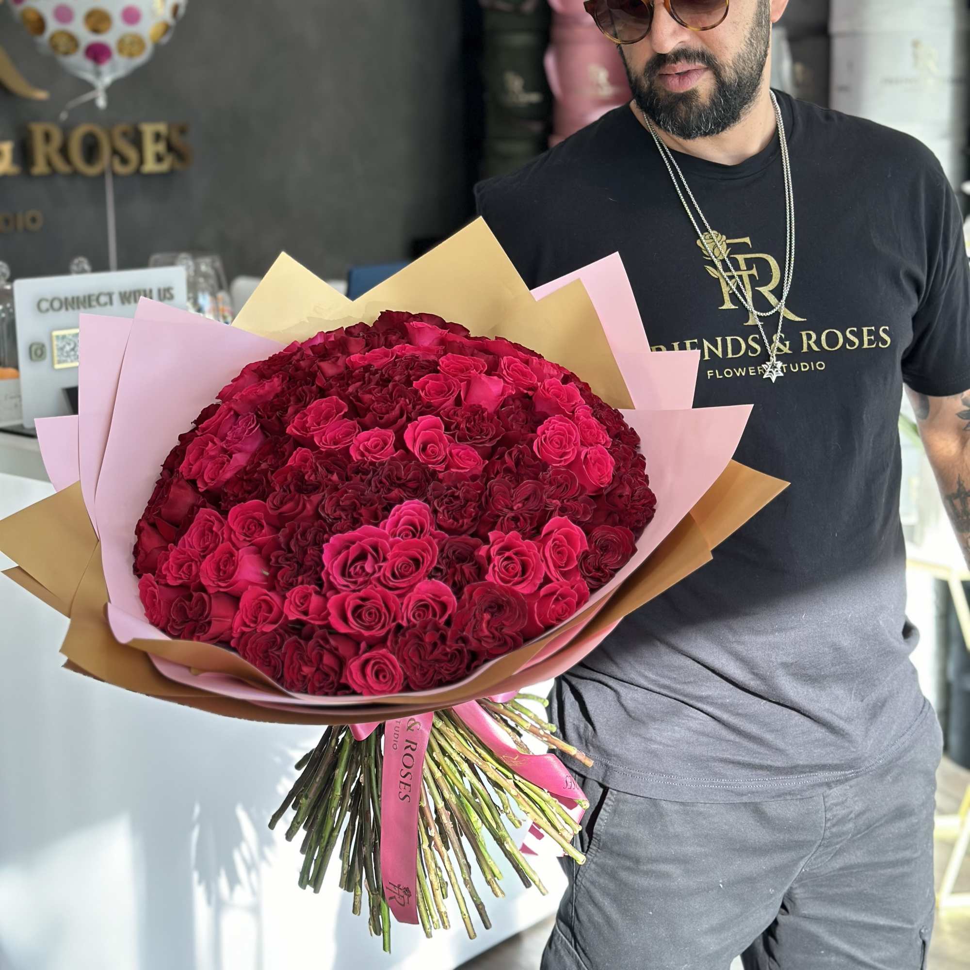Large bouquet of deep pink roses wrapped in pink and gold paper