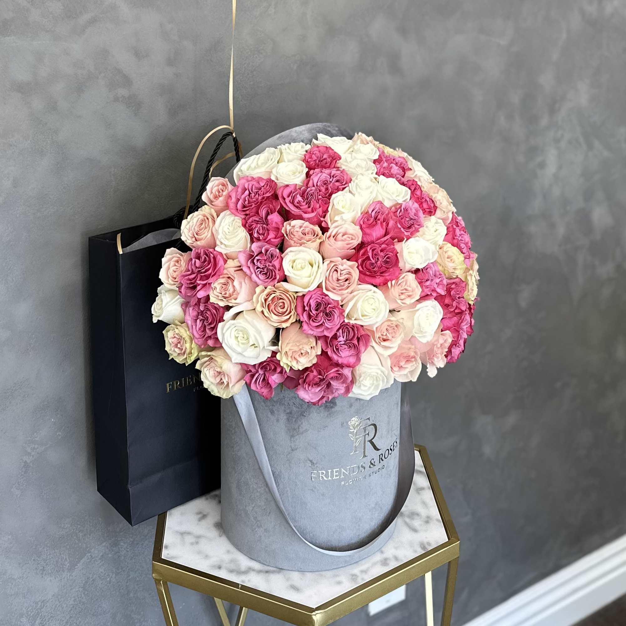 Round bouquet of pink and white roses in a gray hat box