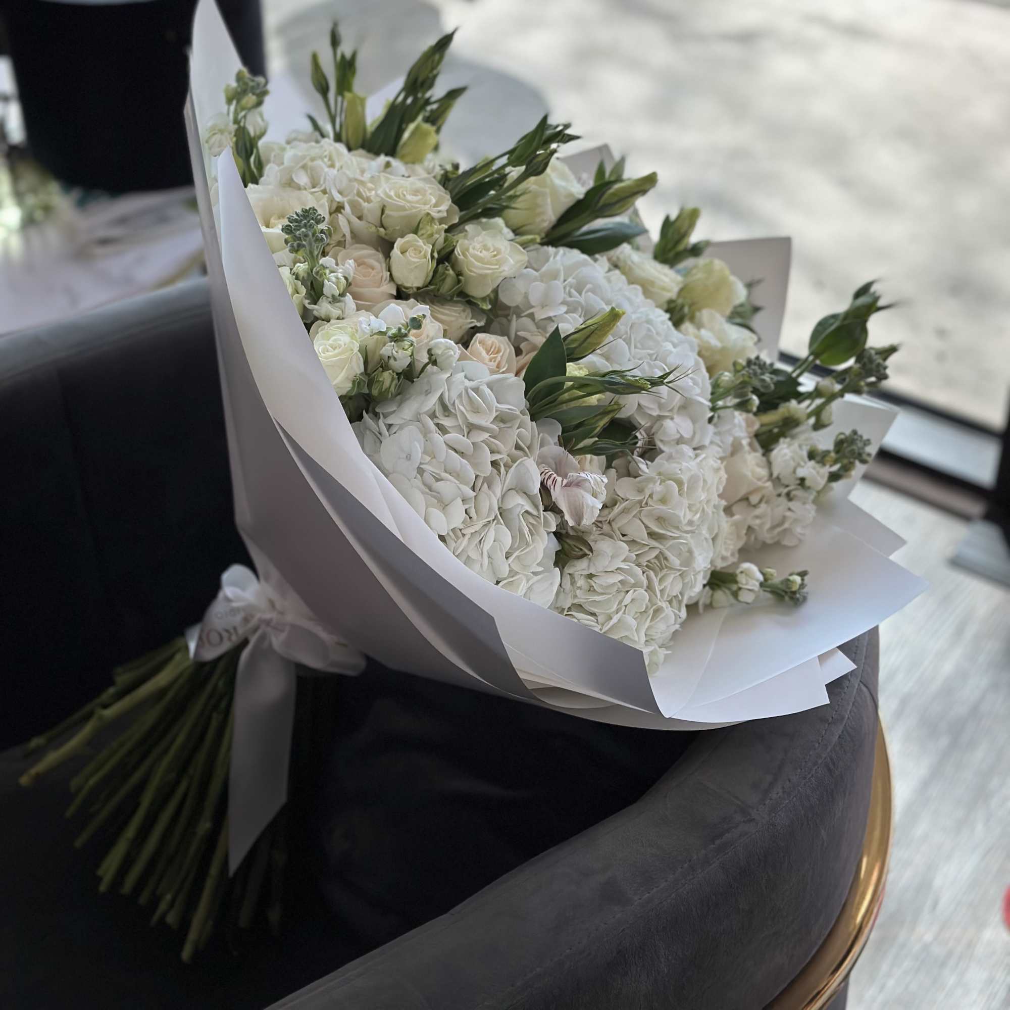 White bouquet of roses and hydrangeas wrapped in paper