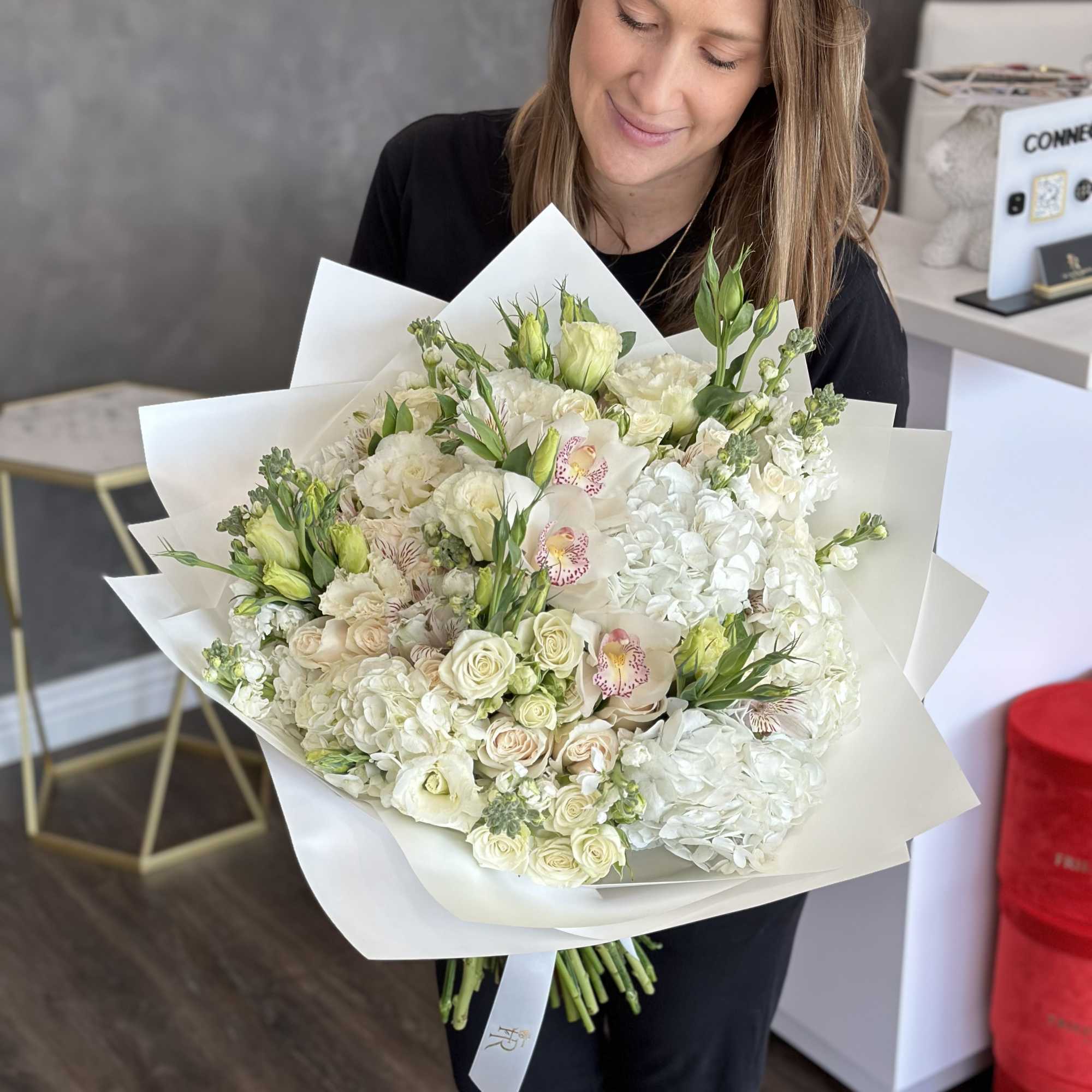 Woman holding a large white bouquet with roses and orchids