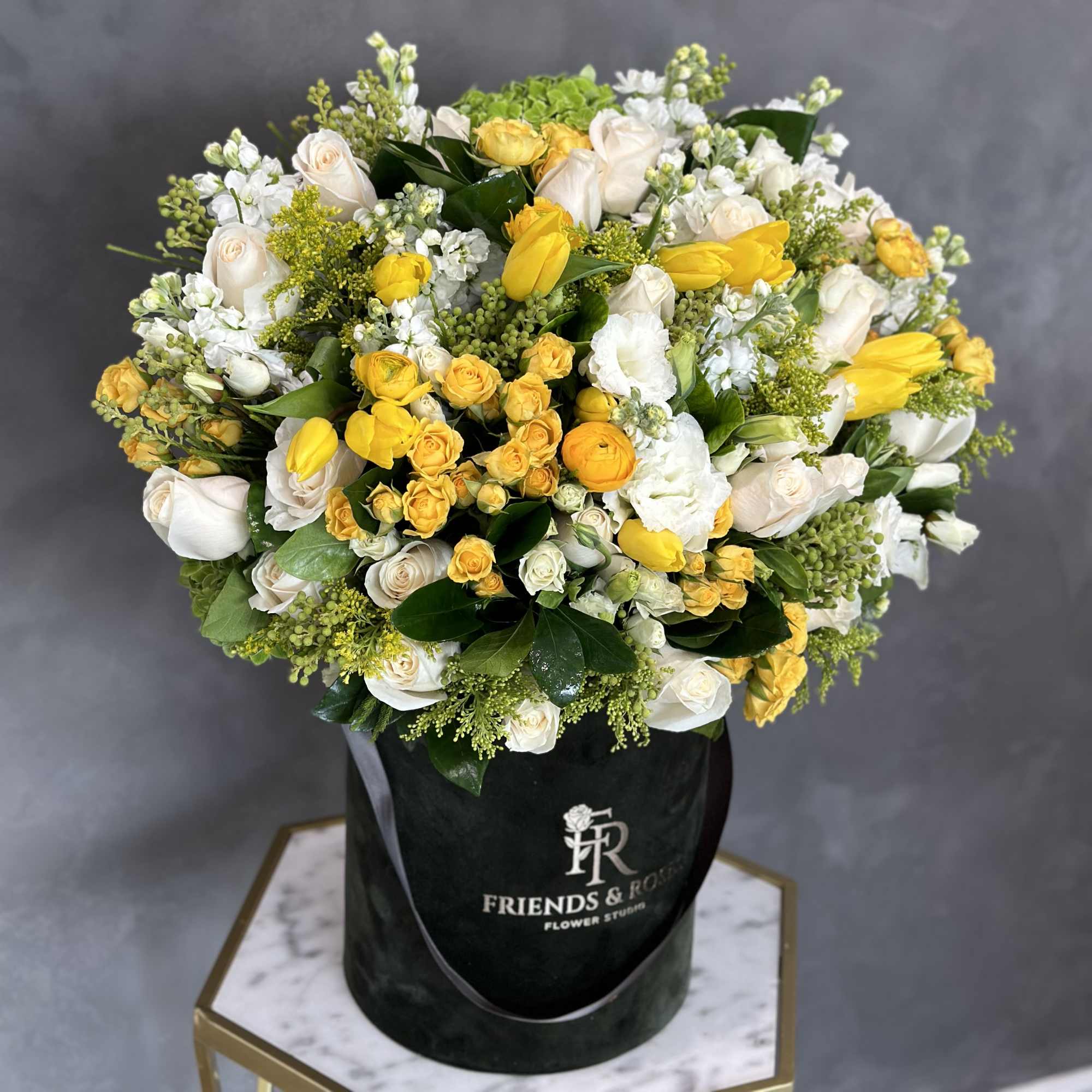 Yellow and white flower bouquet in a black hat box