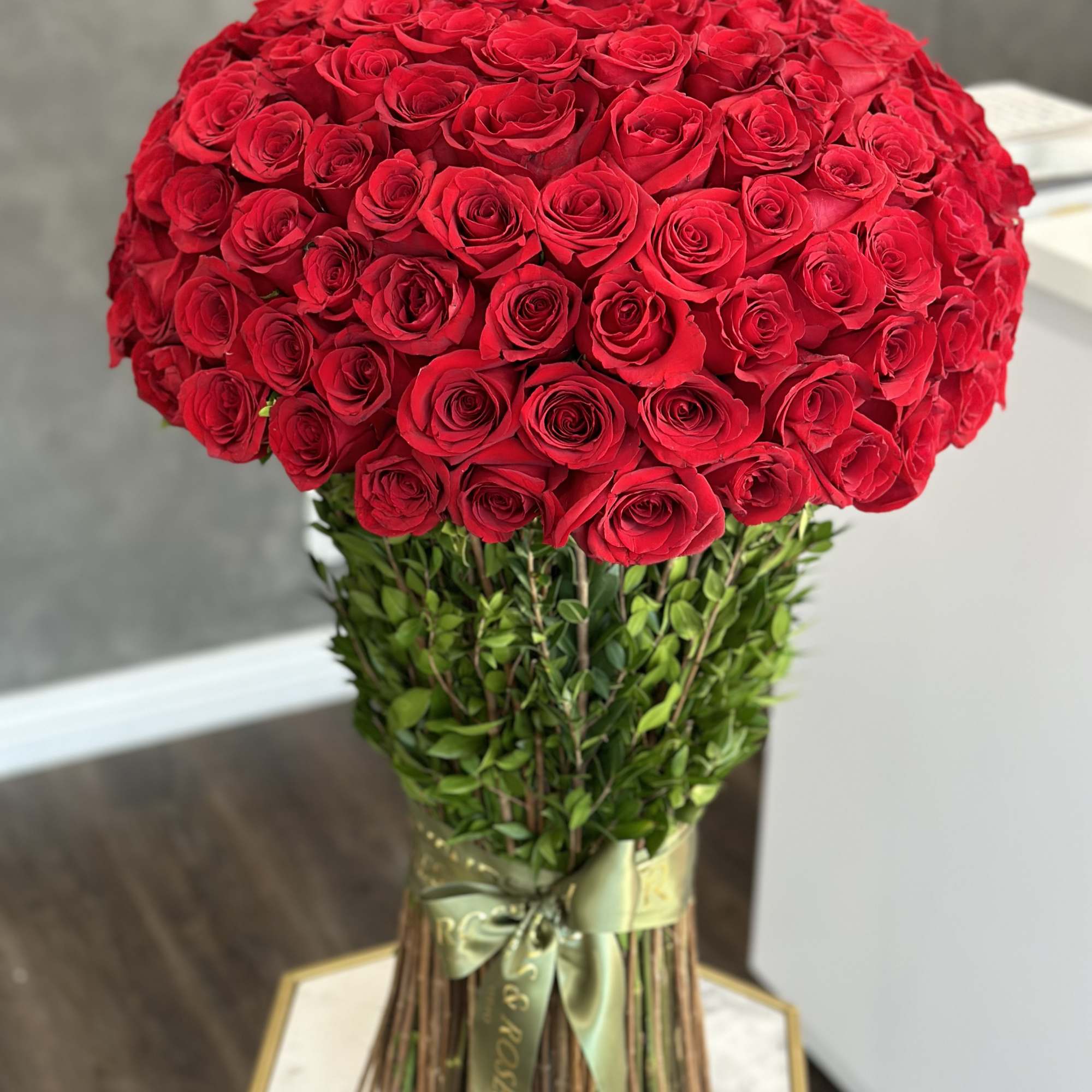 Large bouquet of red roses with a ribbon-wrapped stem bundle