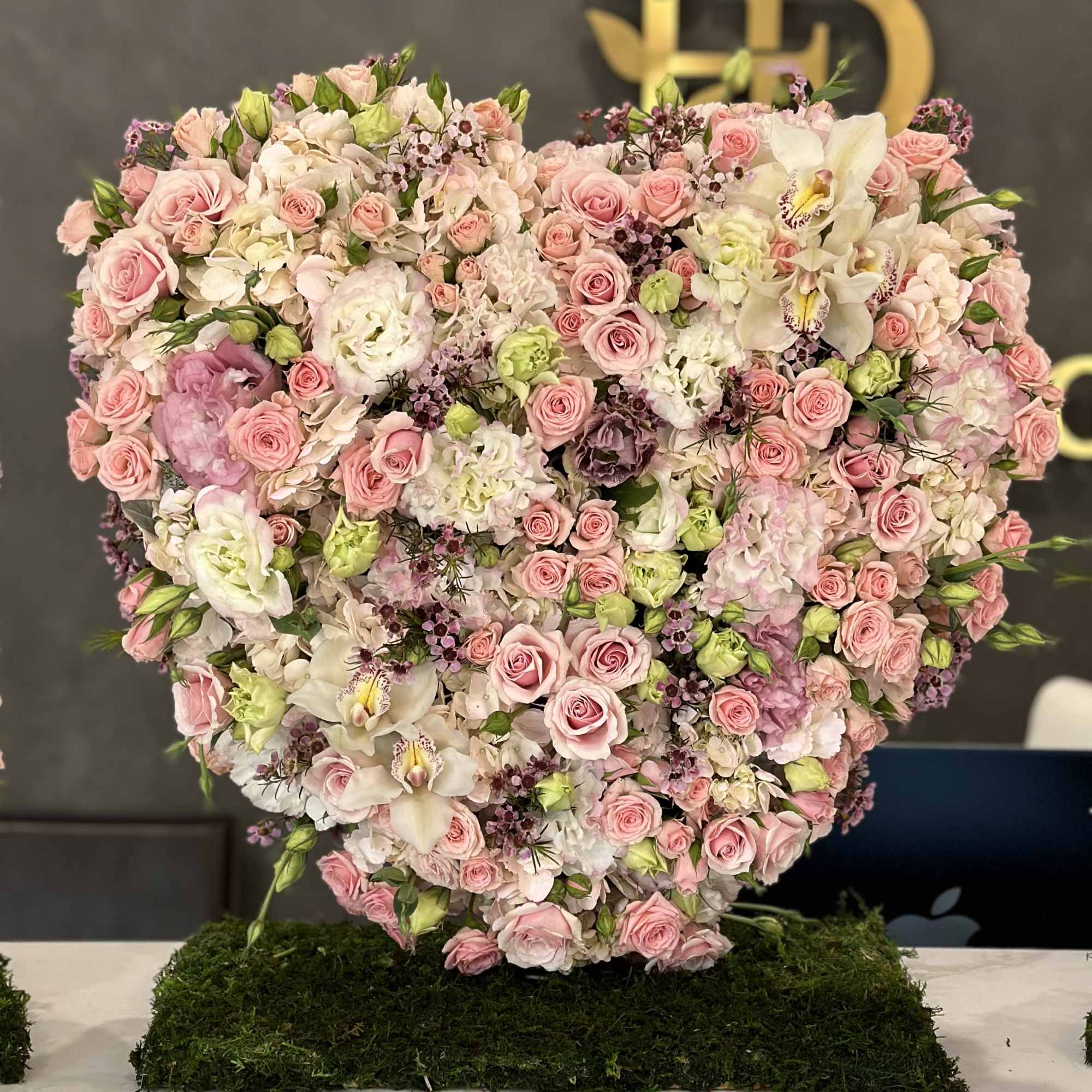 Heart-shaped arrangement of pink and white flowers on a moss base