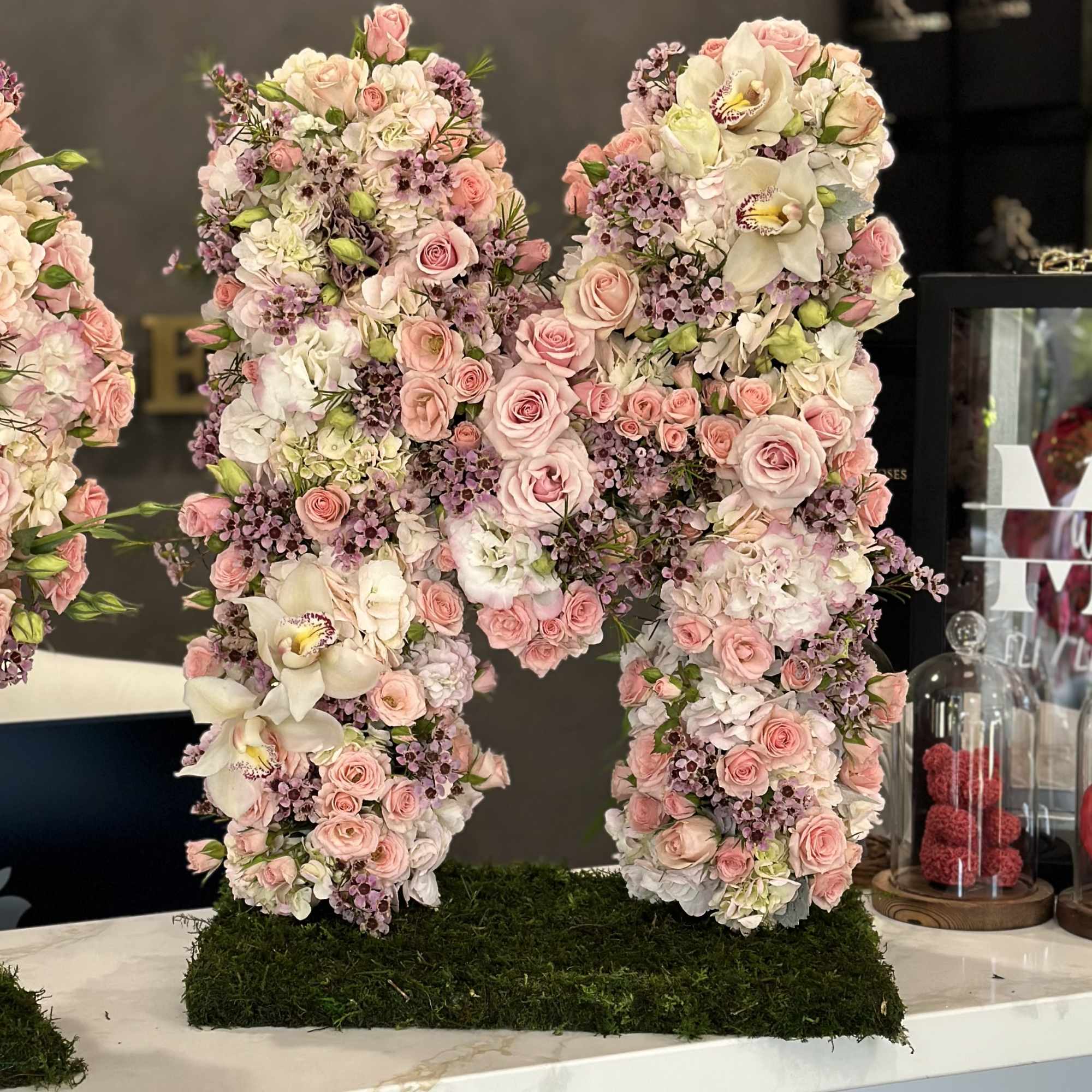 Large floral letter M covered in pink and white flowers