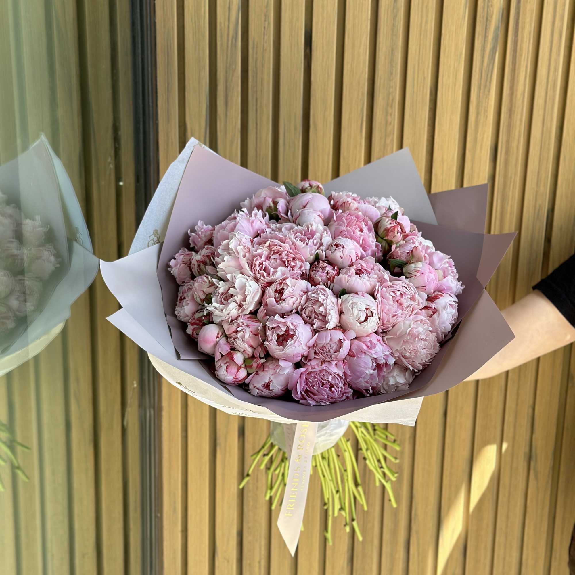 Bouquet of pink peonies wrapped in pastel paper