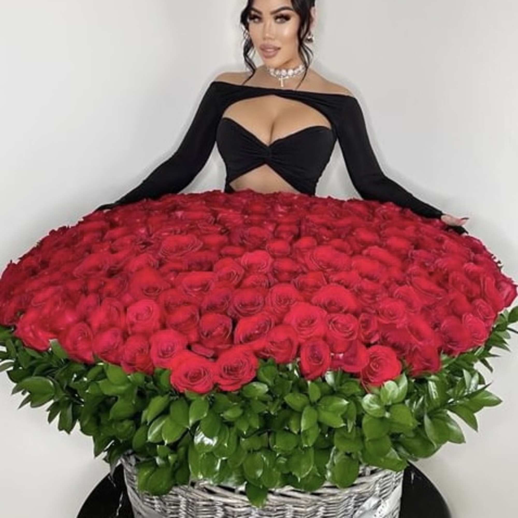 Woman posing behind a large basket of red roses
