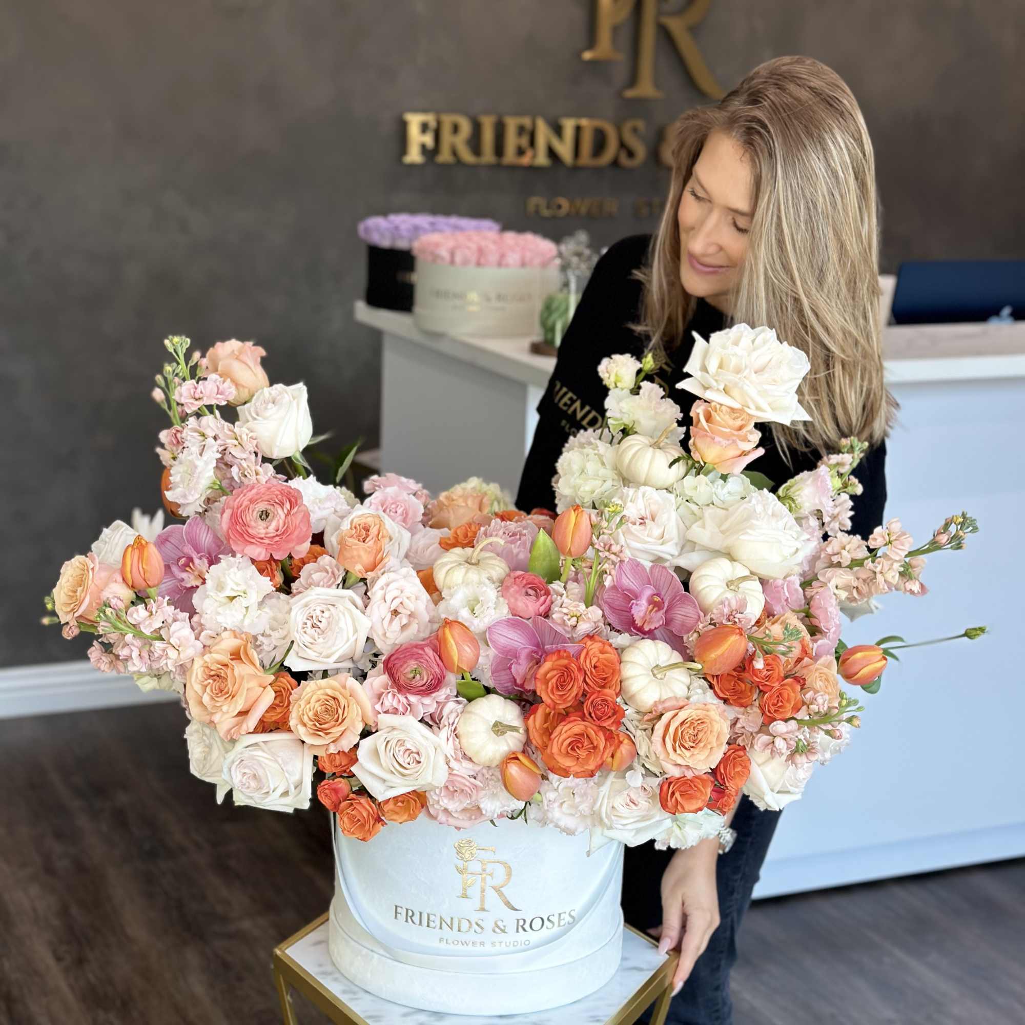 Large pastel flower arrangement in a white hat box with roses and orchids