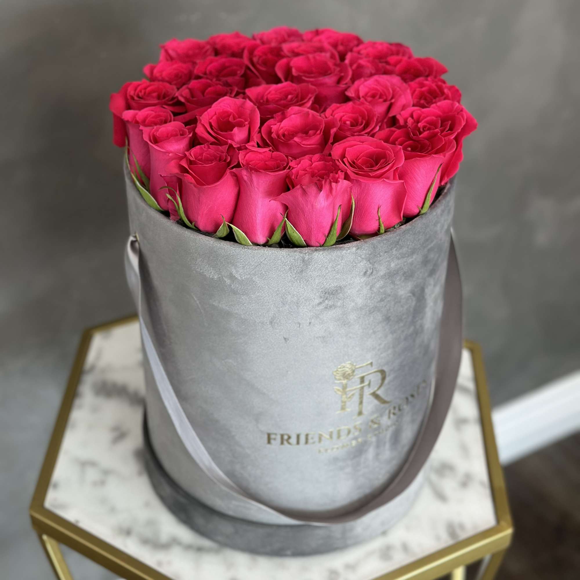 Hot pink roses arranged in a gray round box