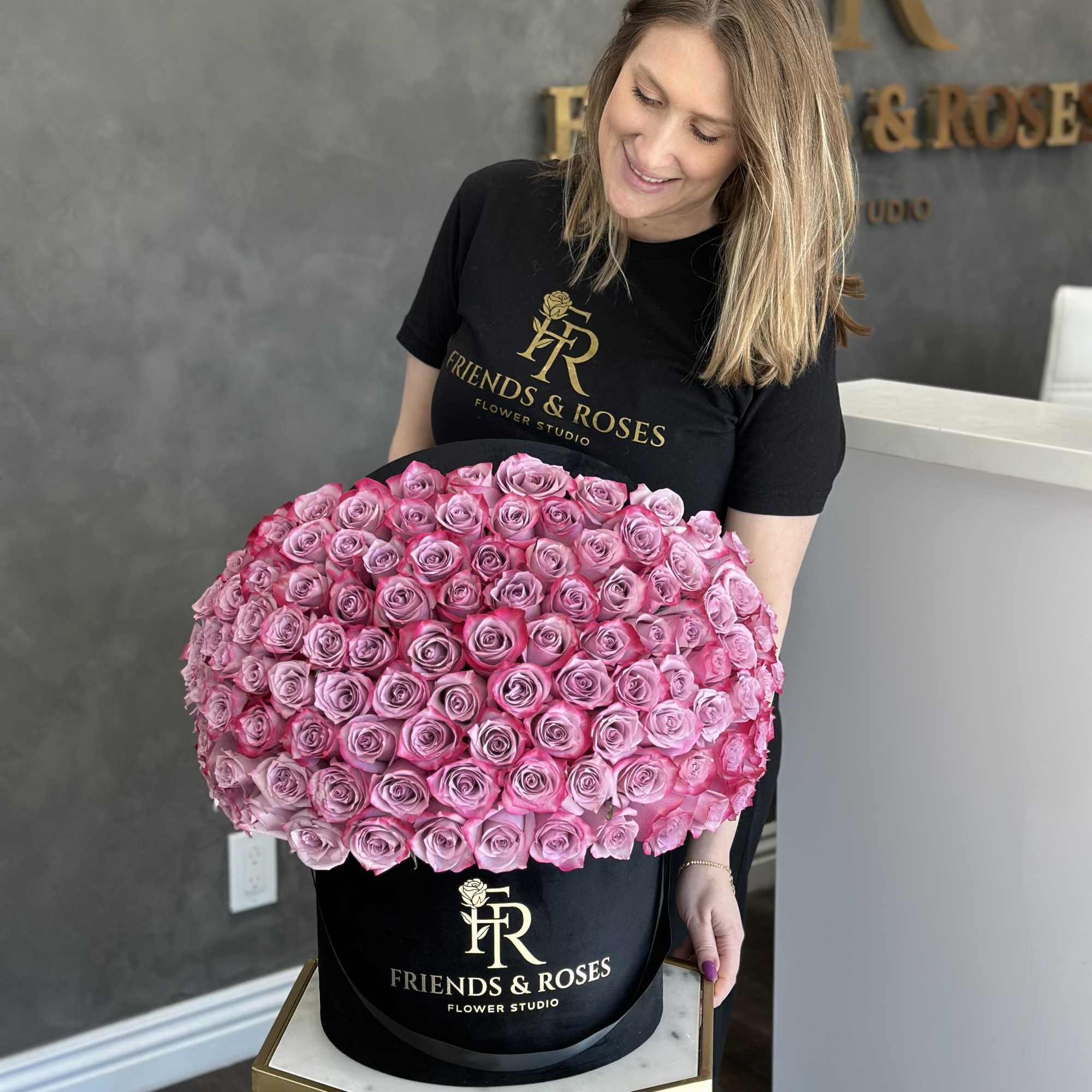 Woman holding a large round box filled with pink roses