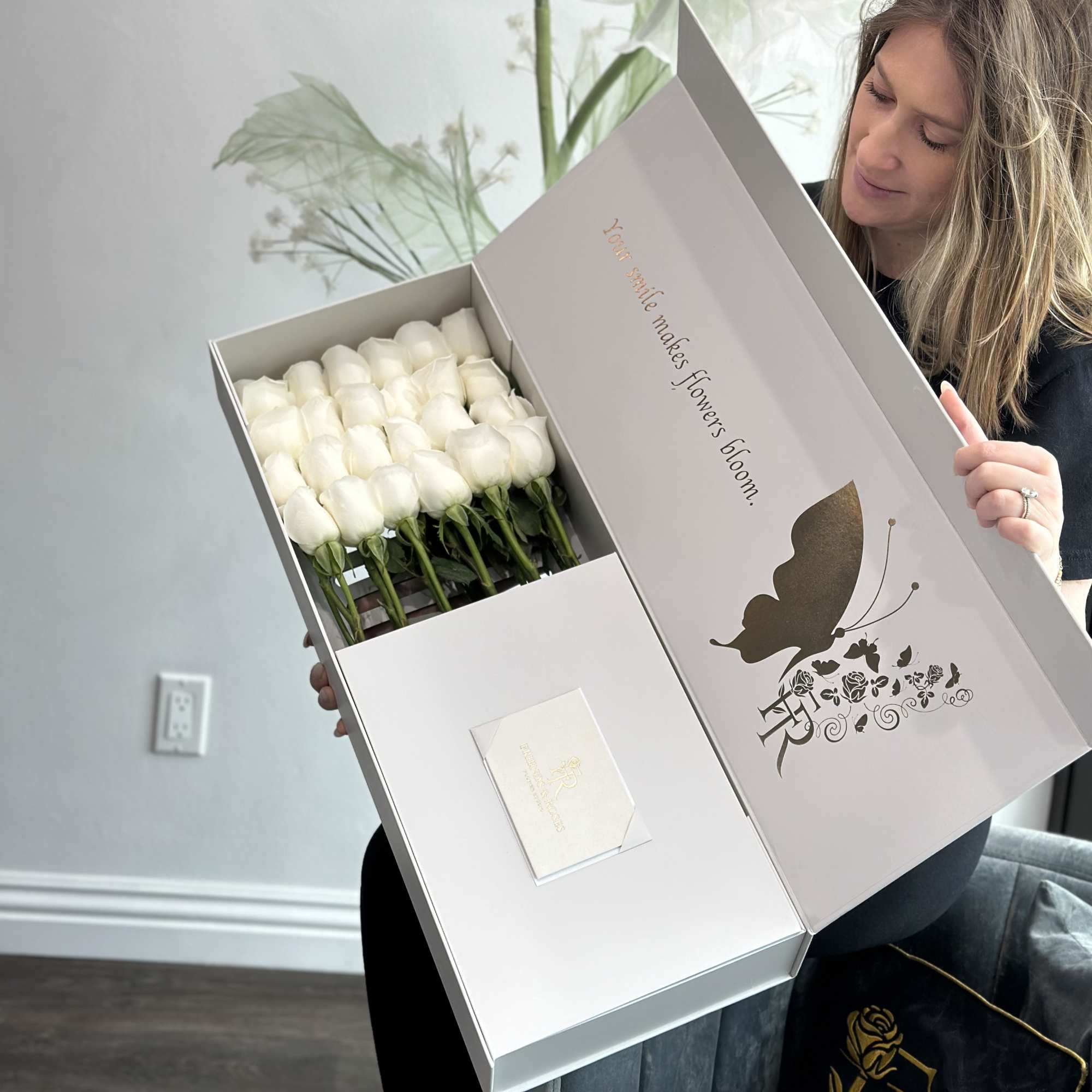 Woman holding a gift box of white roses with a card inside