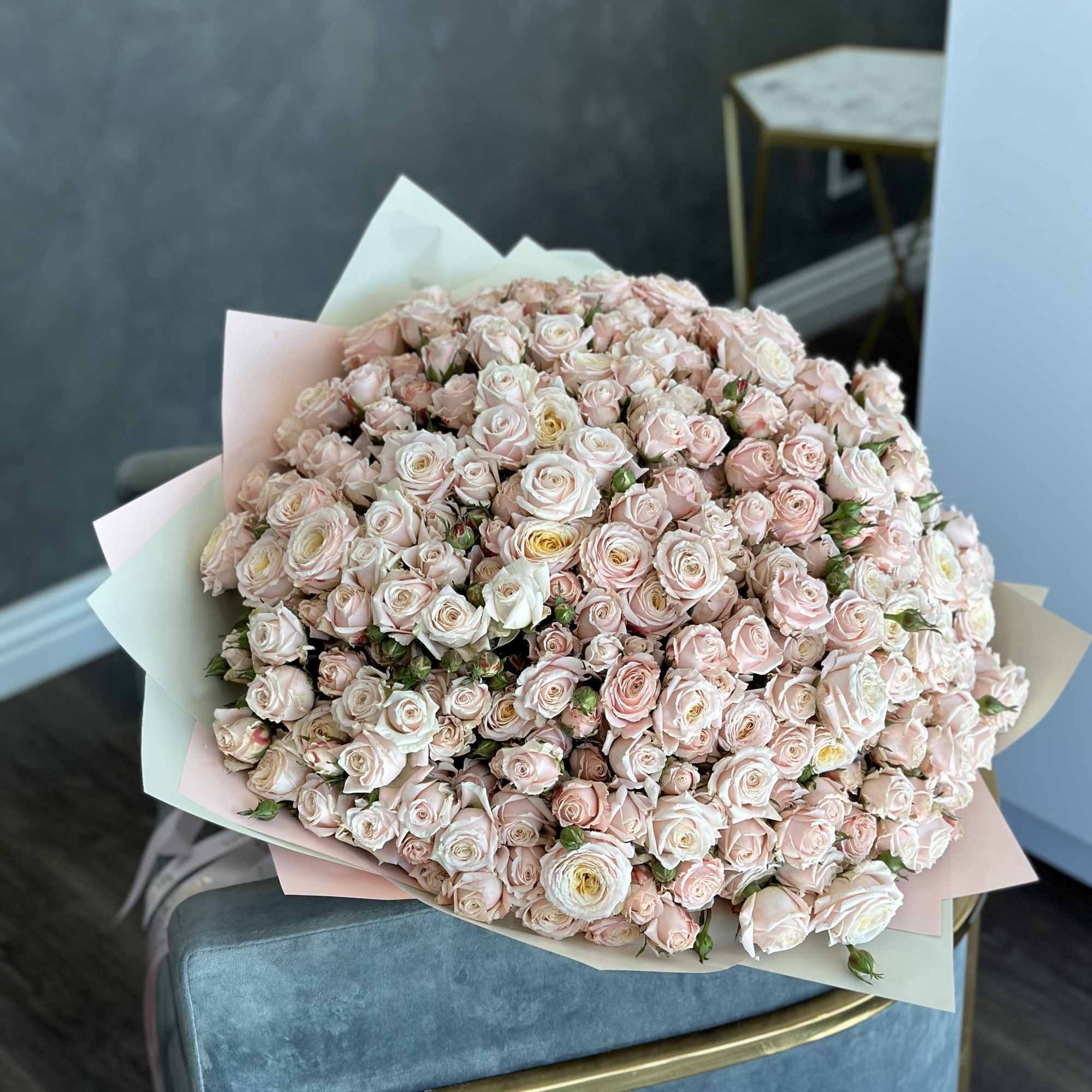 Large bouquet of pale pink and white roses wrapped in pastel paper