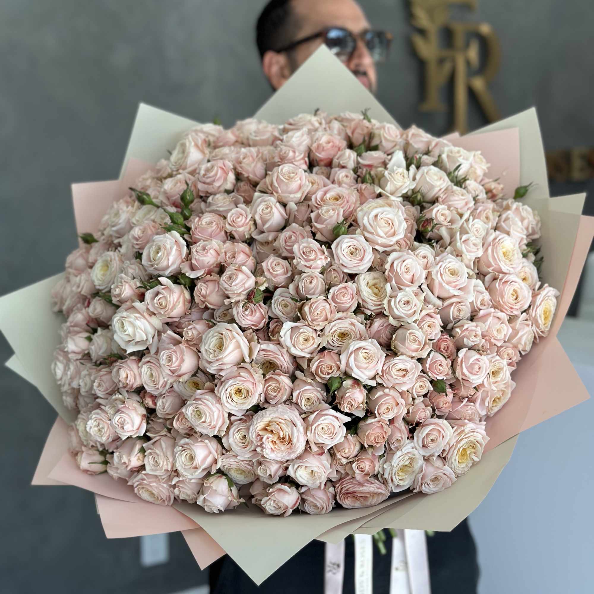 Large bouquet of pale pink roses wrapped in pastel paper