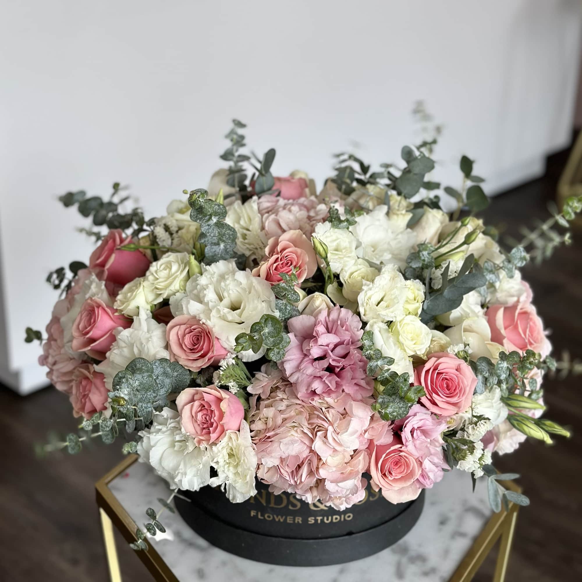 Large pink and white flower arrangement in a black hat box