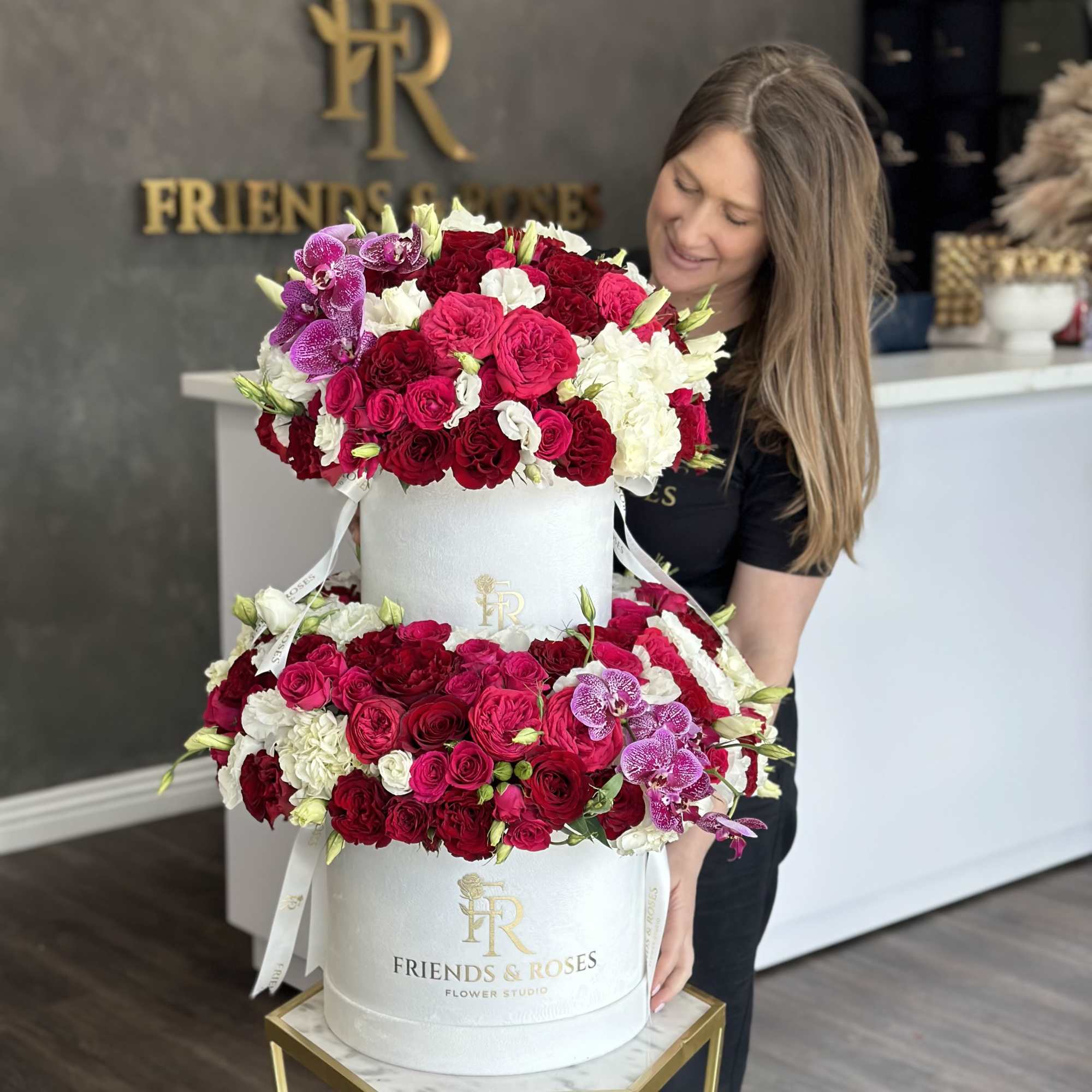 Two-tier hatbox arrangement of red, pink, white, and purple flowers