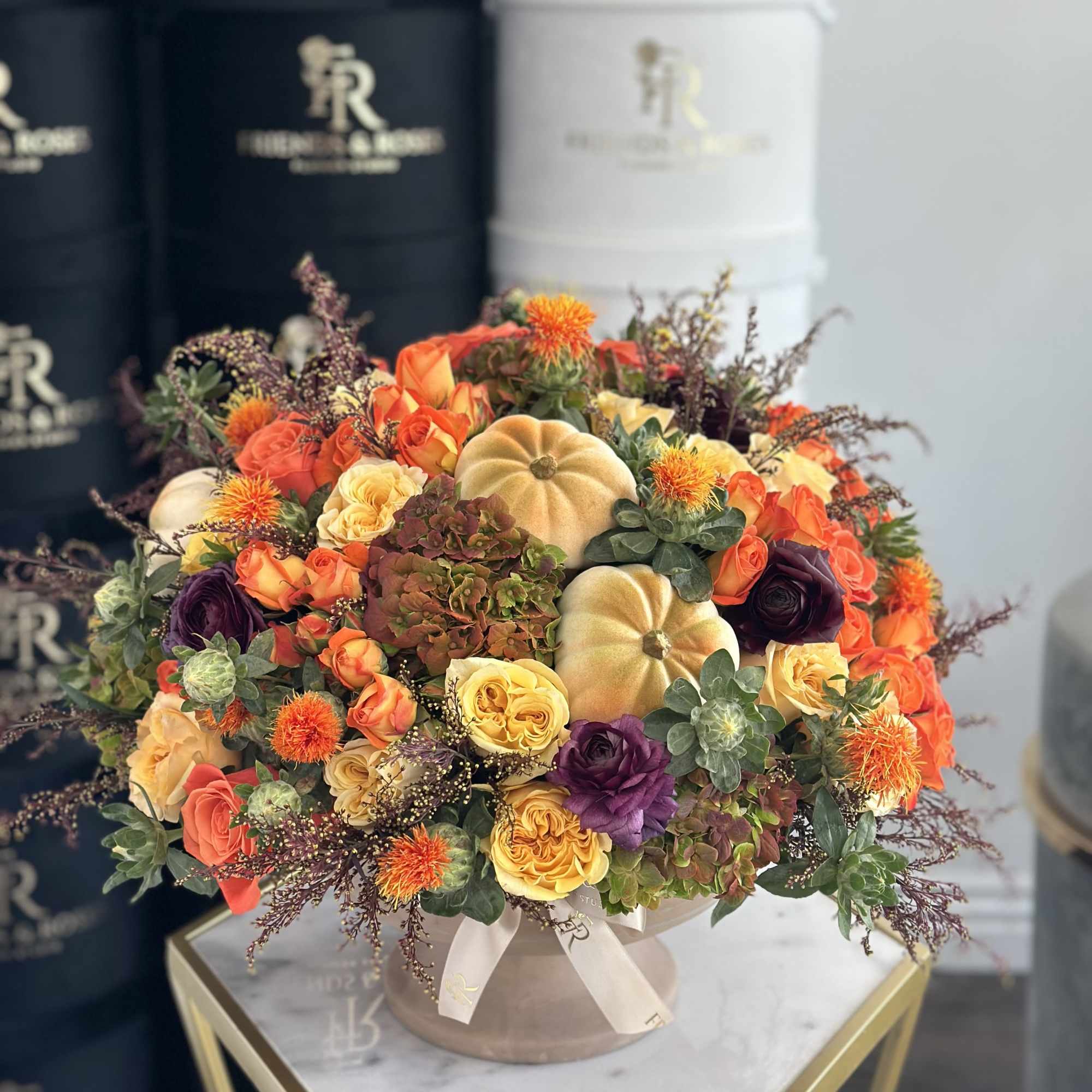 Orange and yellow roses with pumpkins in a round vase