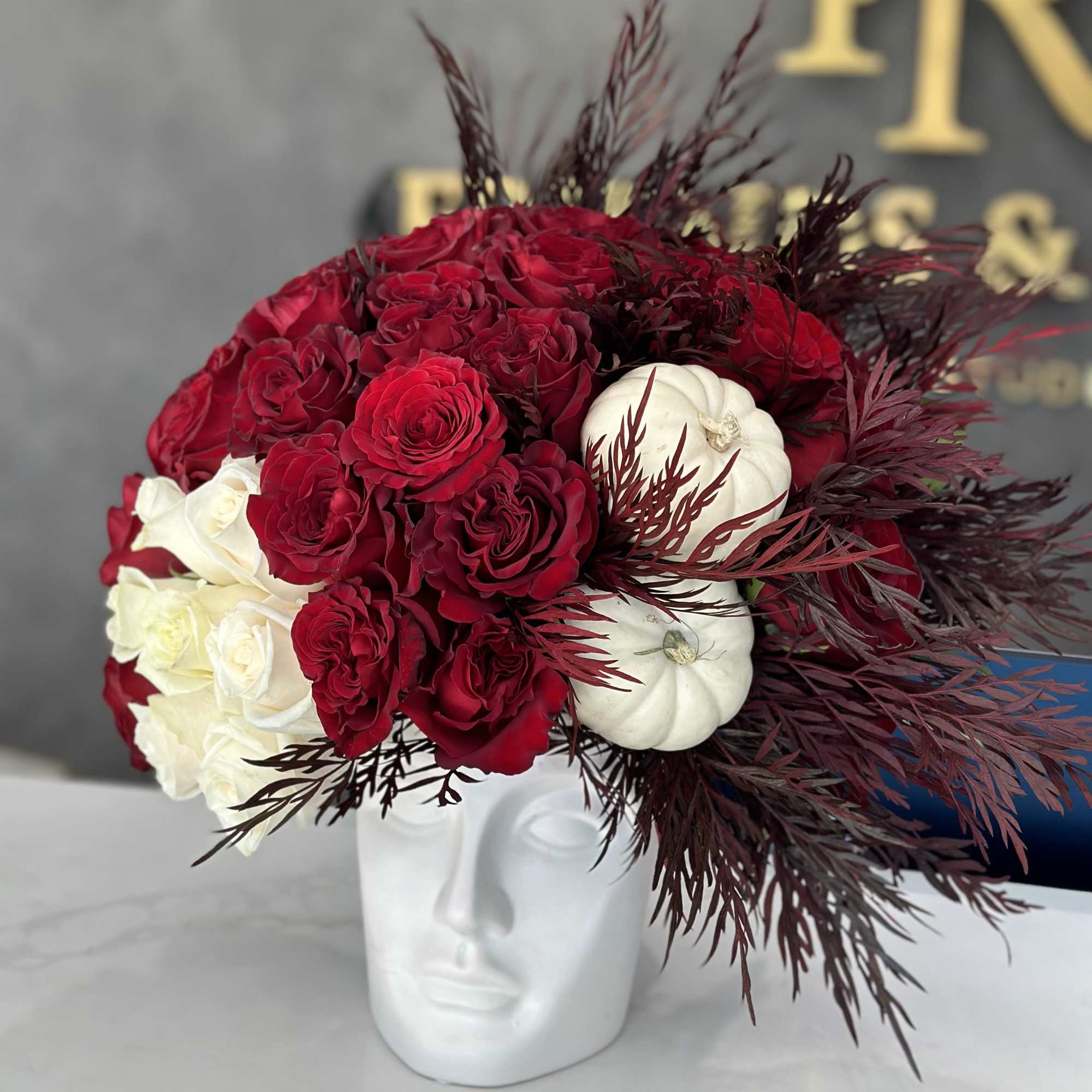 Red and white rose arrangement in a white face vase
