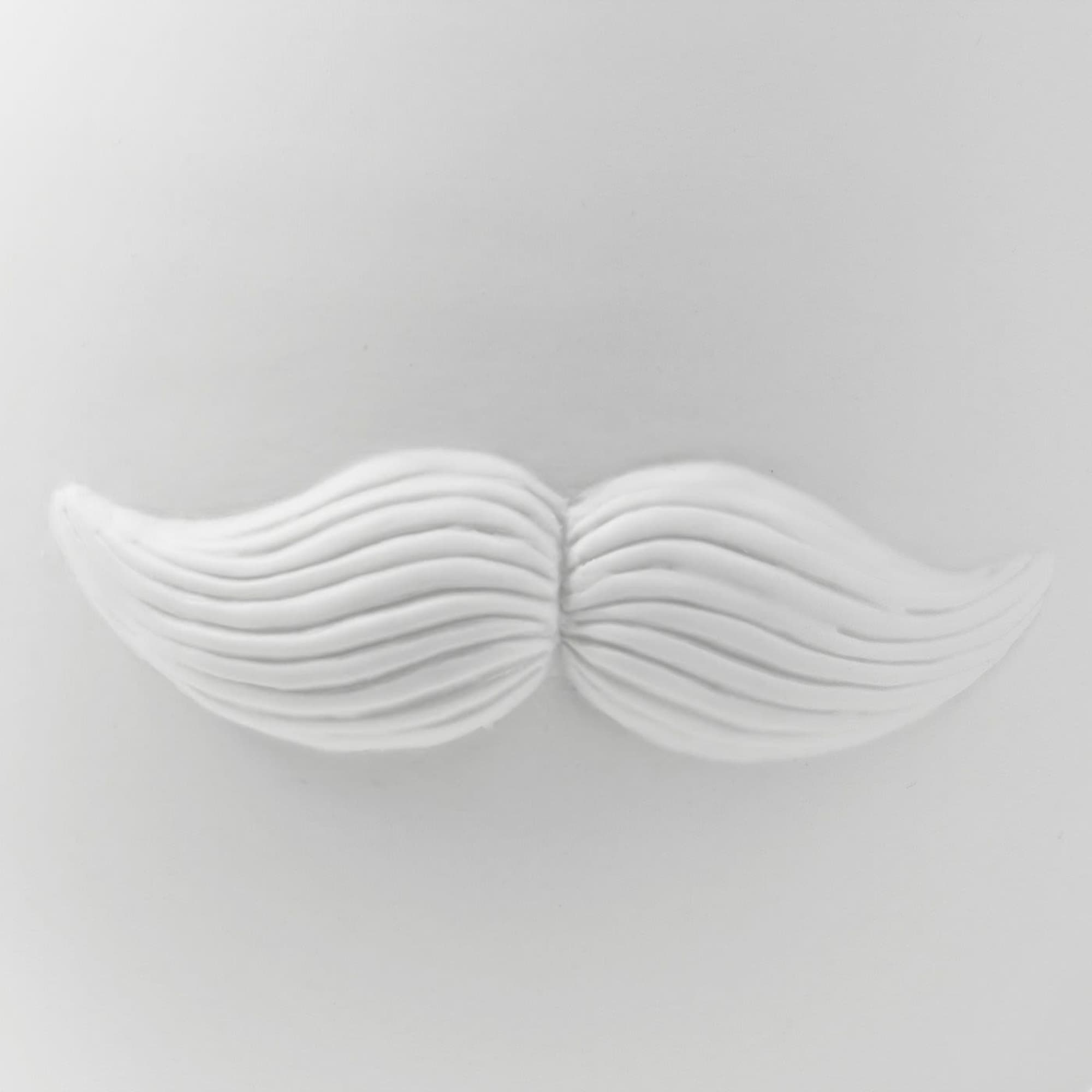 White decorative wall piece shaped like a mustache