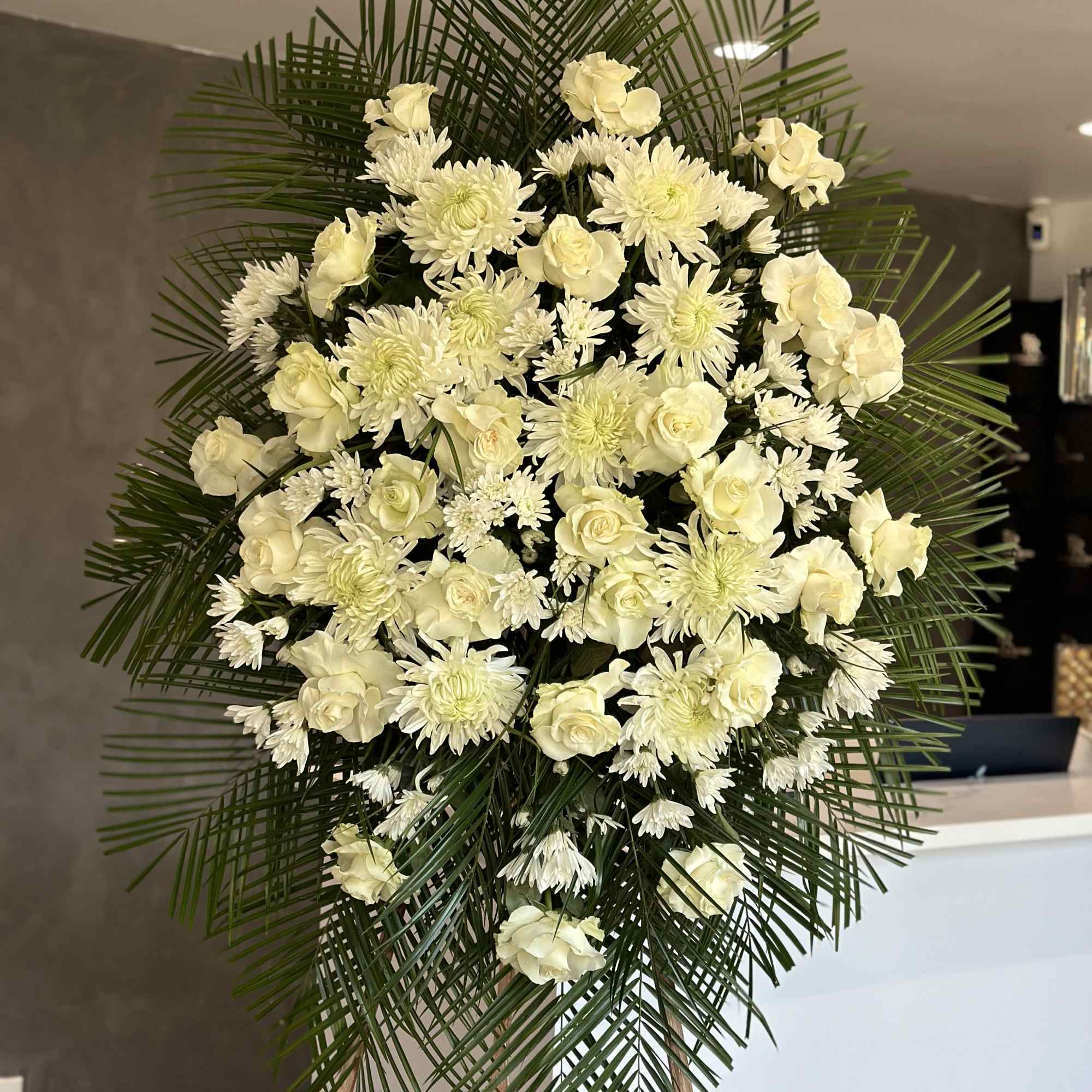 White floral standing spray with roses and chrysanthemums on an easel