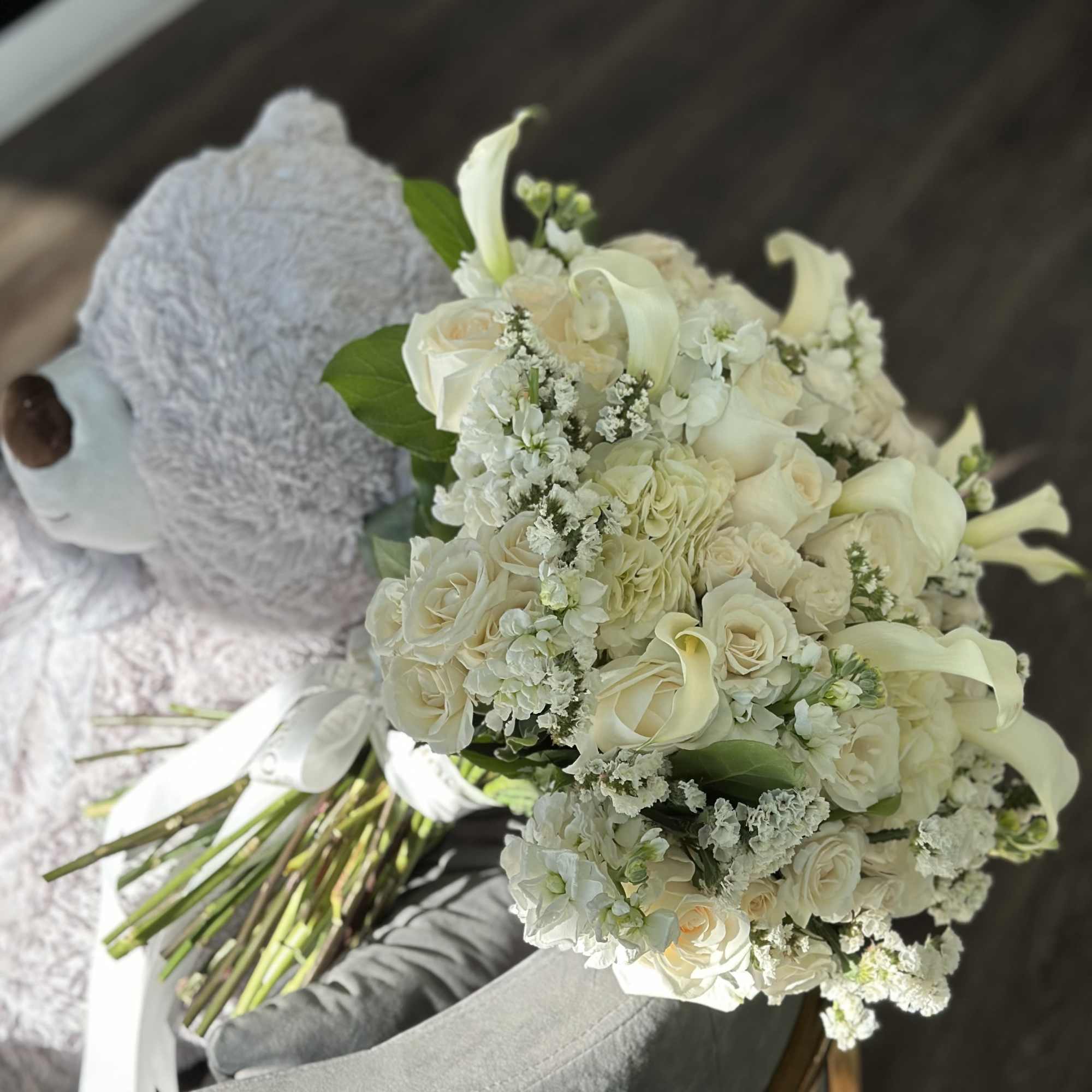 White bridal bouquet with roses, calla lilies, and a teddy bear