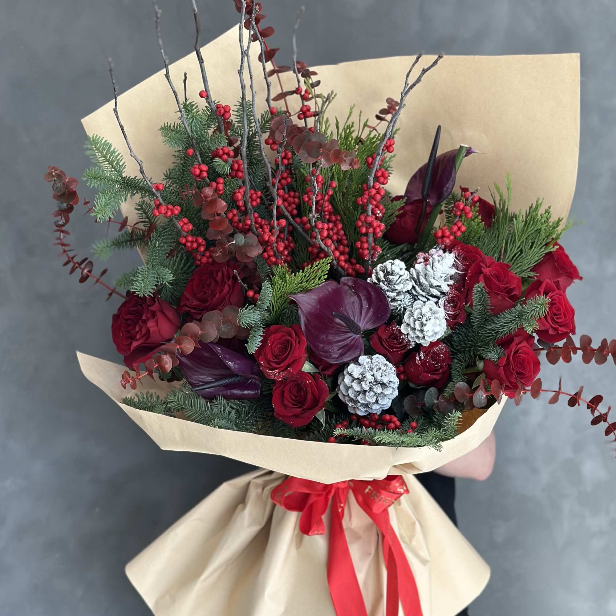 Bouquet of red roses with burgundy calla lilies and berries in kraft paper